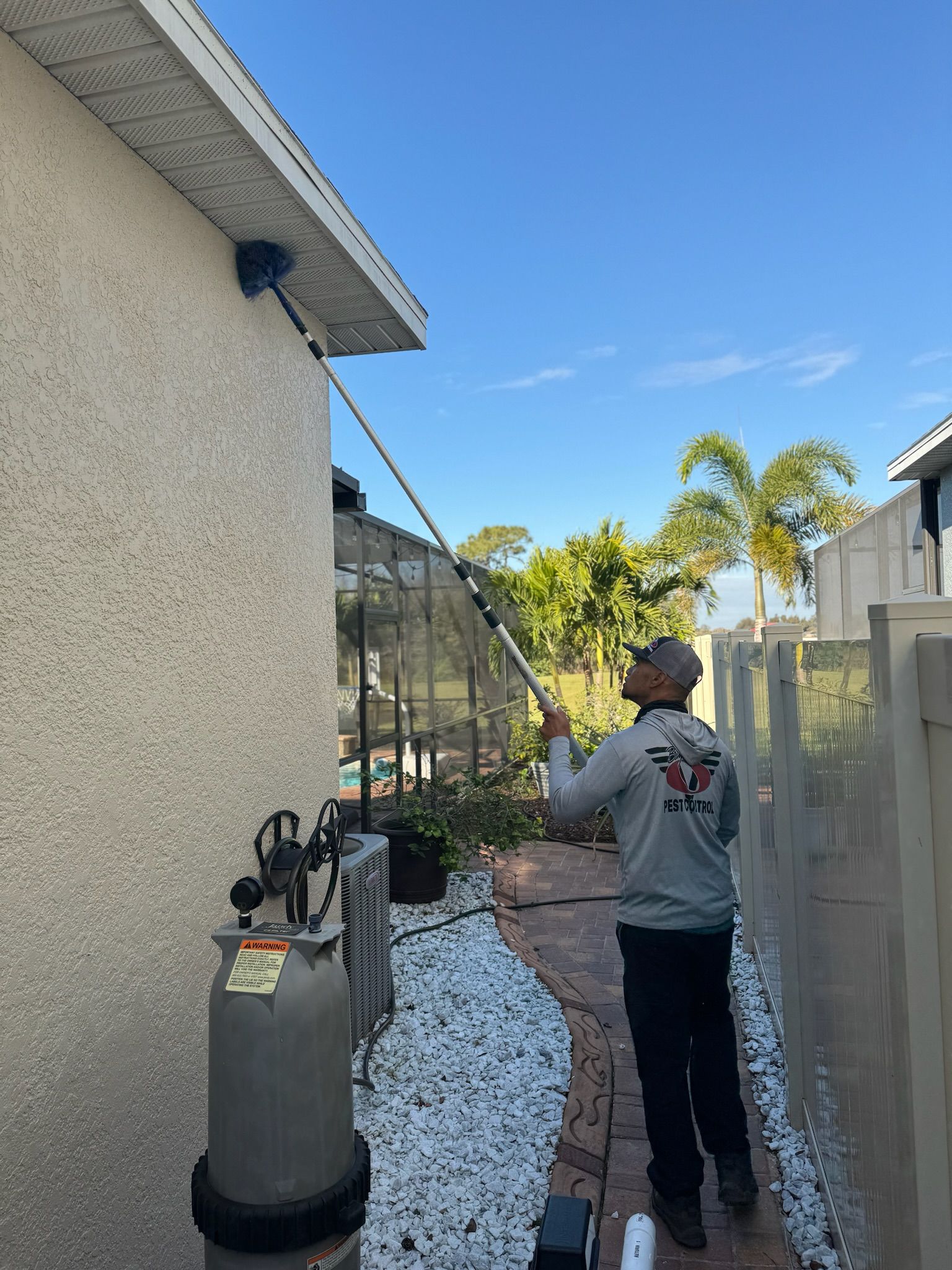 A man is cleaning the side of a house with a high pressure washer.