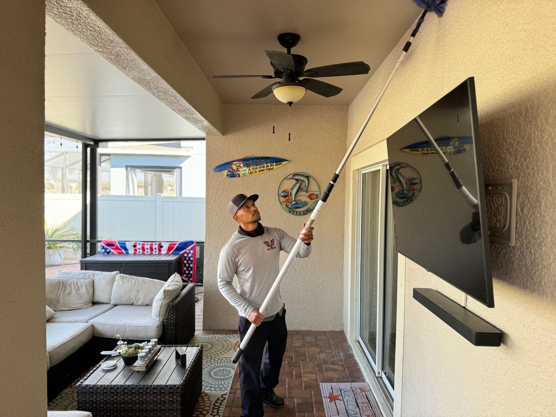 A man is cleaning the ceiling of a living room with a broom.
