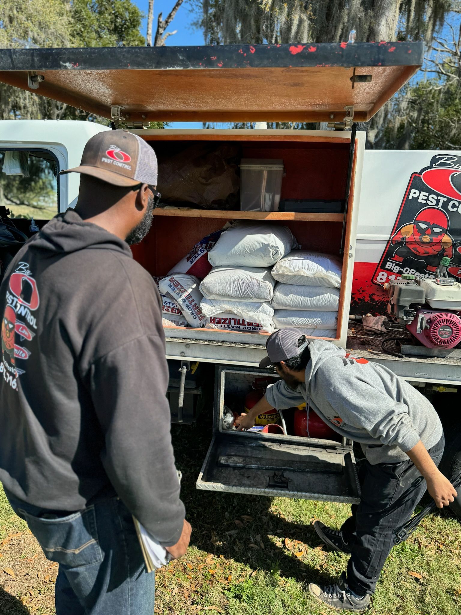 Two men are looking into the back of a truck.
