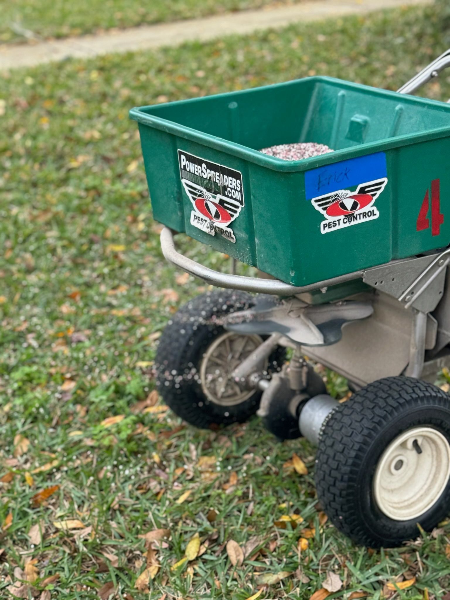 A green spreader is sitting on top of a lush green lawn.