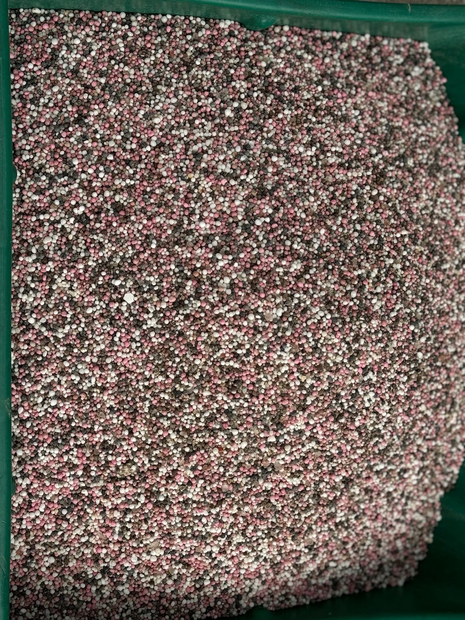 A pile of small stones is sitting in a green container.