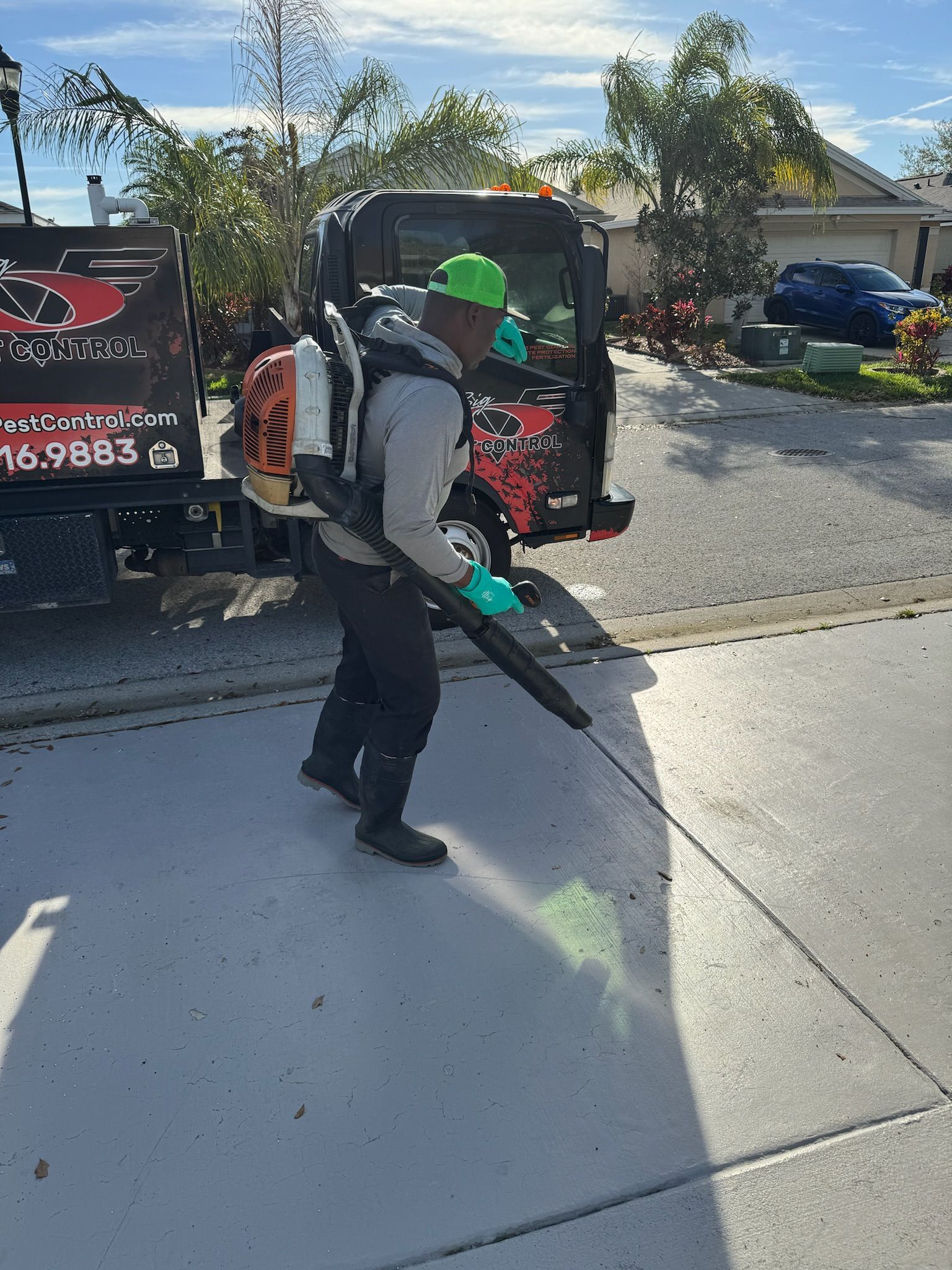A man is spraying a sidewalk with a blower.