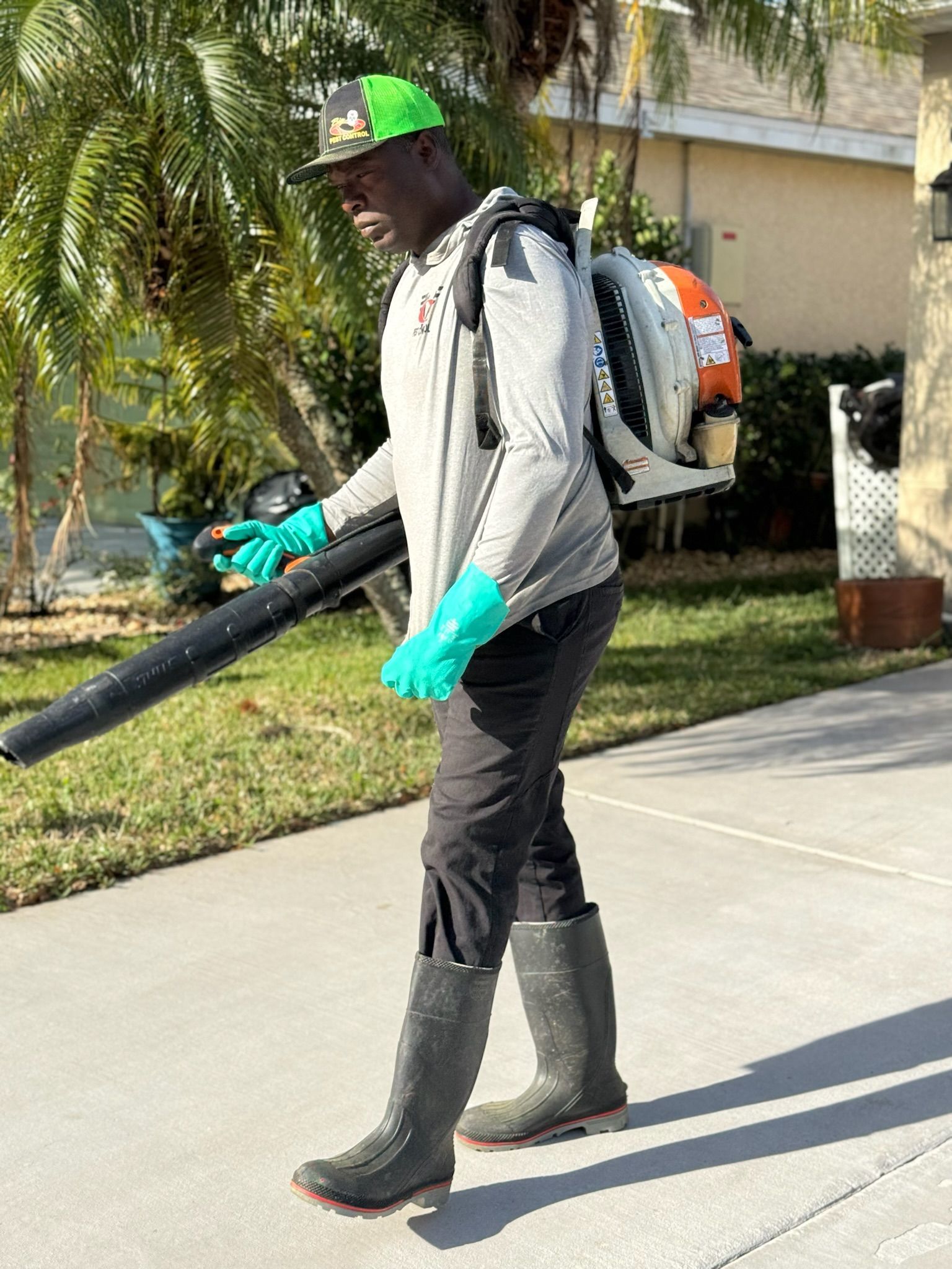A man is walking down a sidewalk holding a blower.