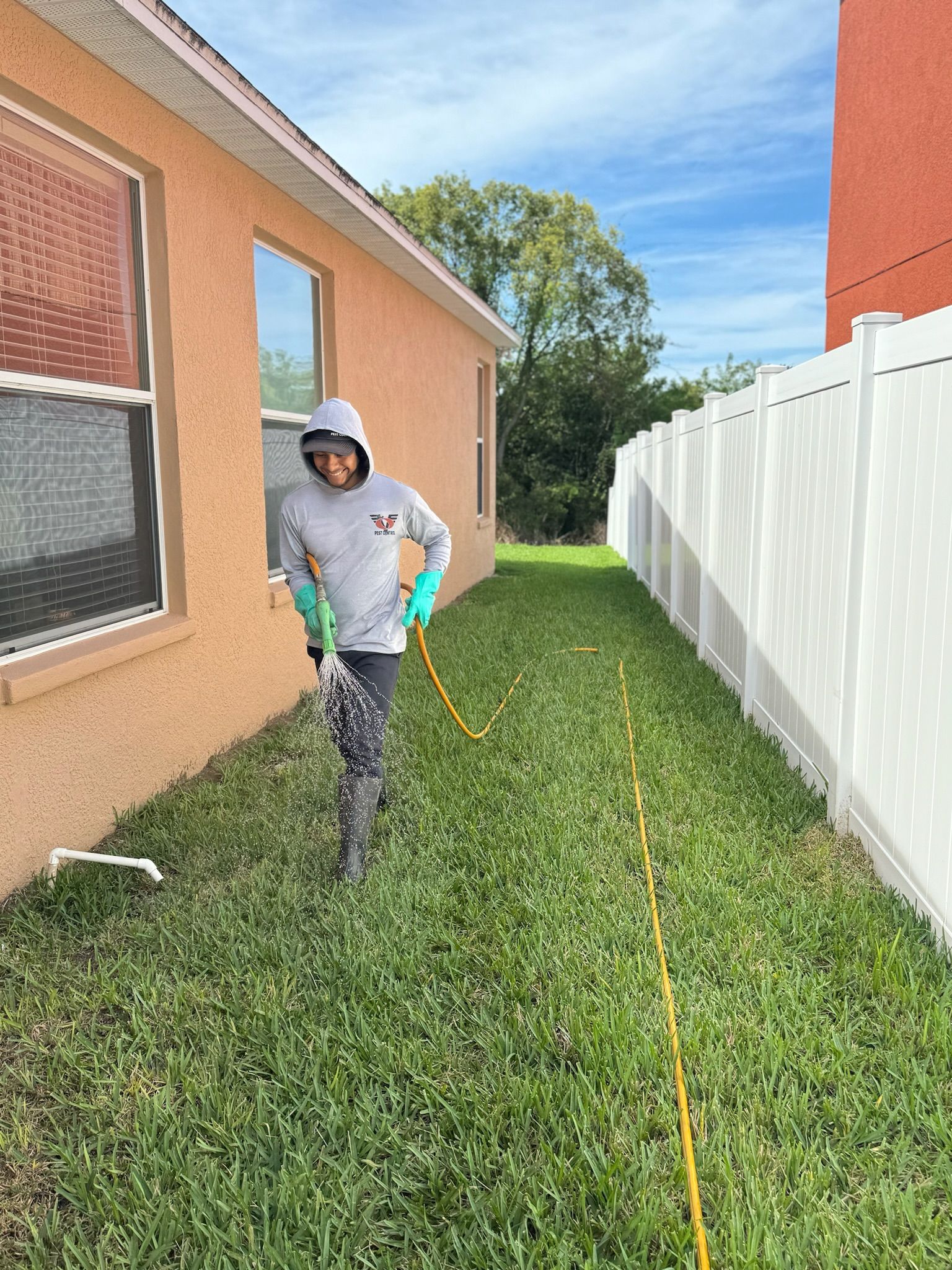 A man is spraying a lawn with a hose in front of a house.