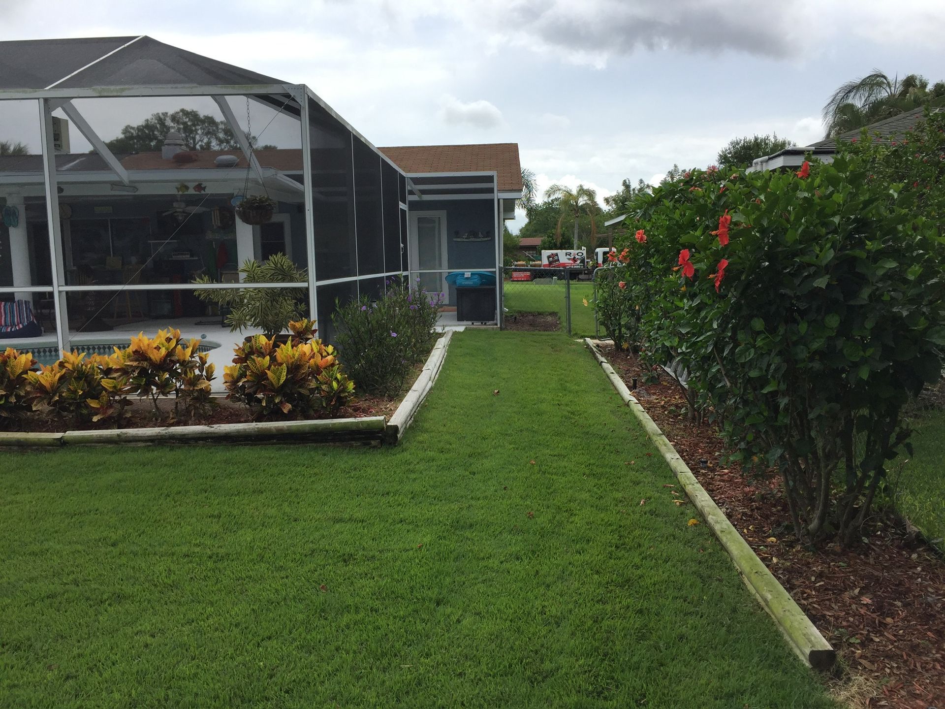 A house with a screened in porch and a lush green lawn.