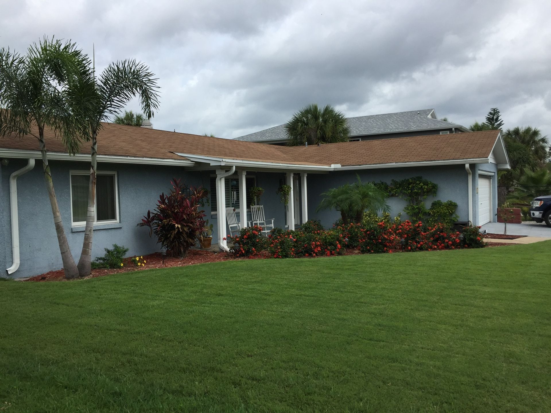 A blue house with a brown roof and a lush green lawn