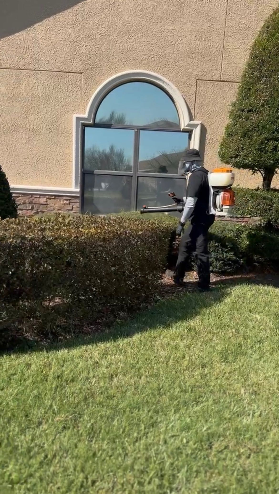 A police officer is walking across a lush green lawn in front of a building.