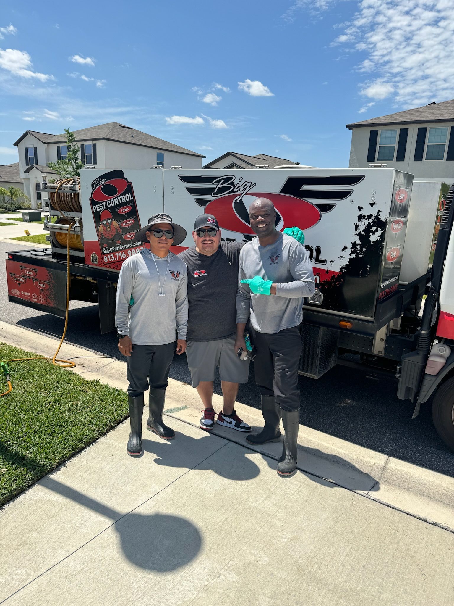 Three men are posing for a picture in front of a truck.
