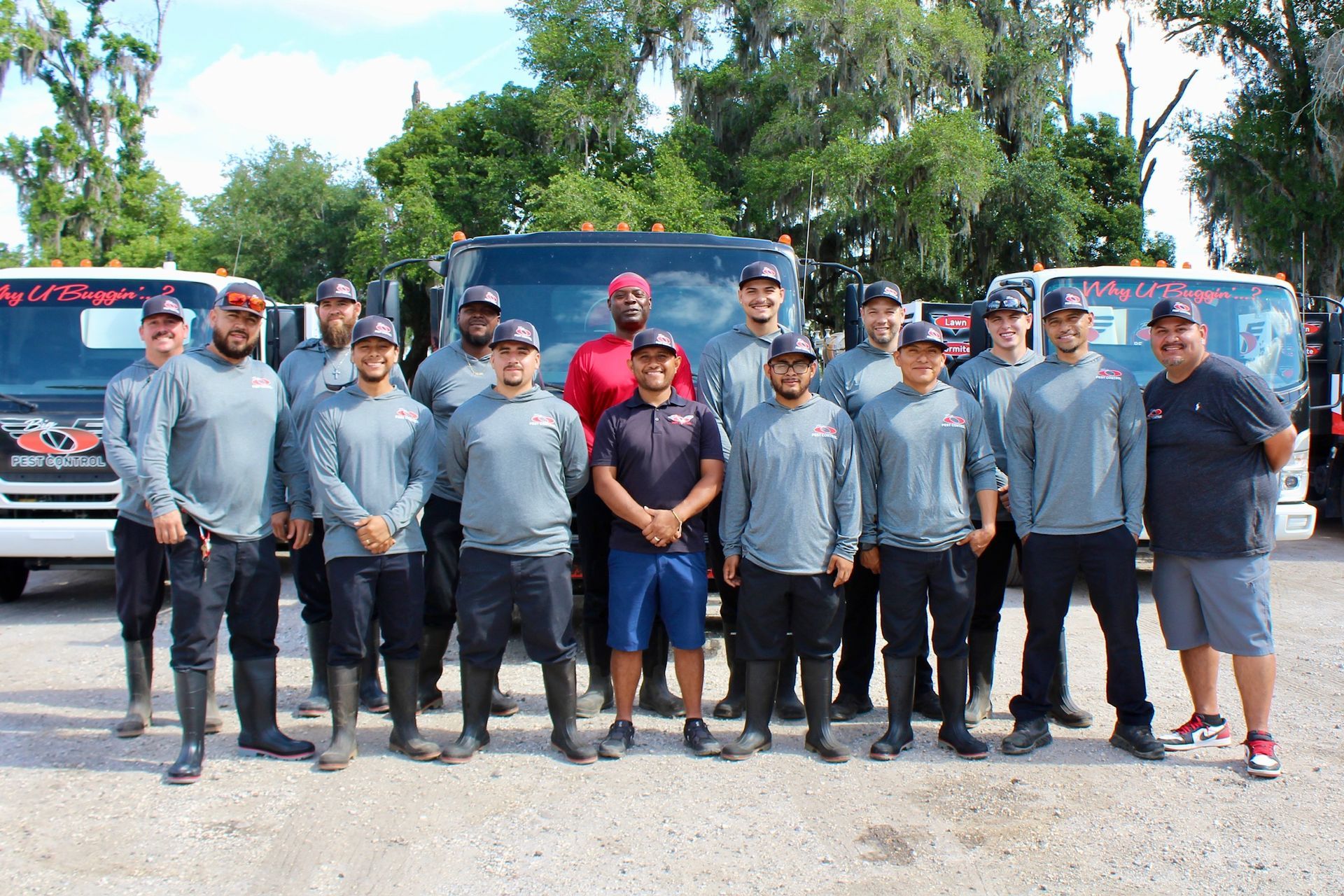 A group of men are posing for a picture in front of trucks.