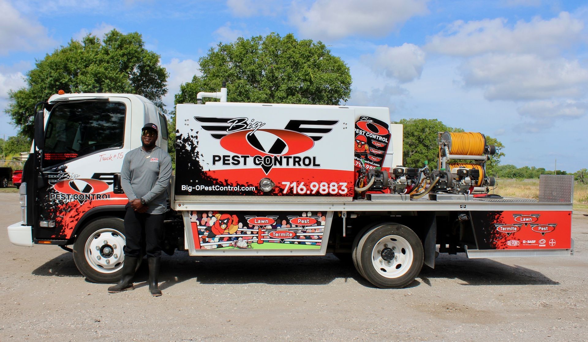 A man is standing next to a pest control truck