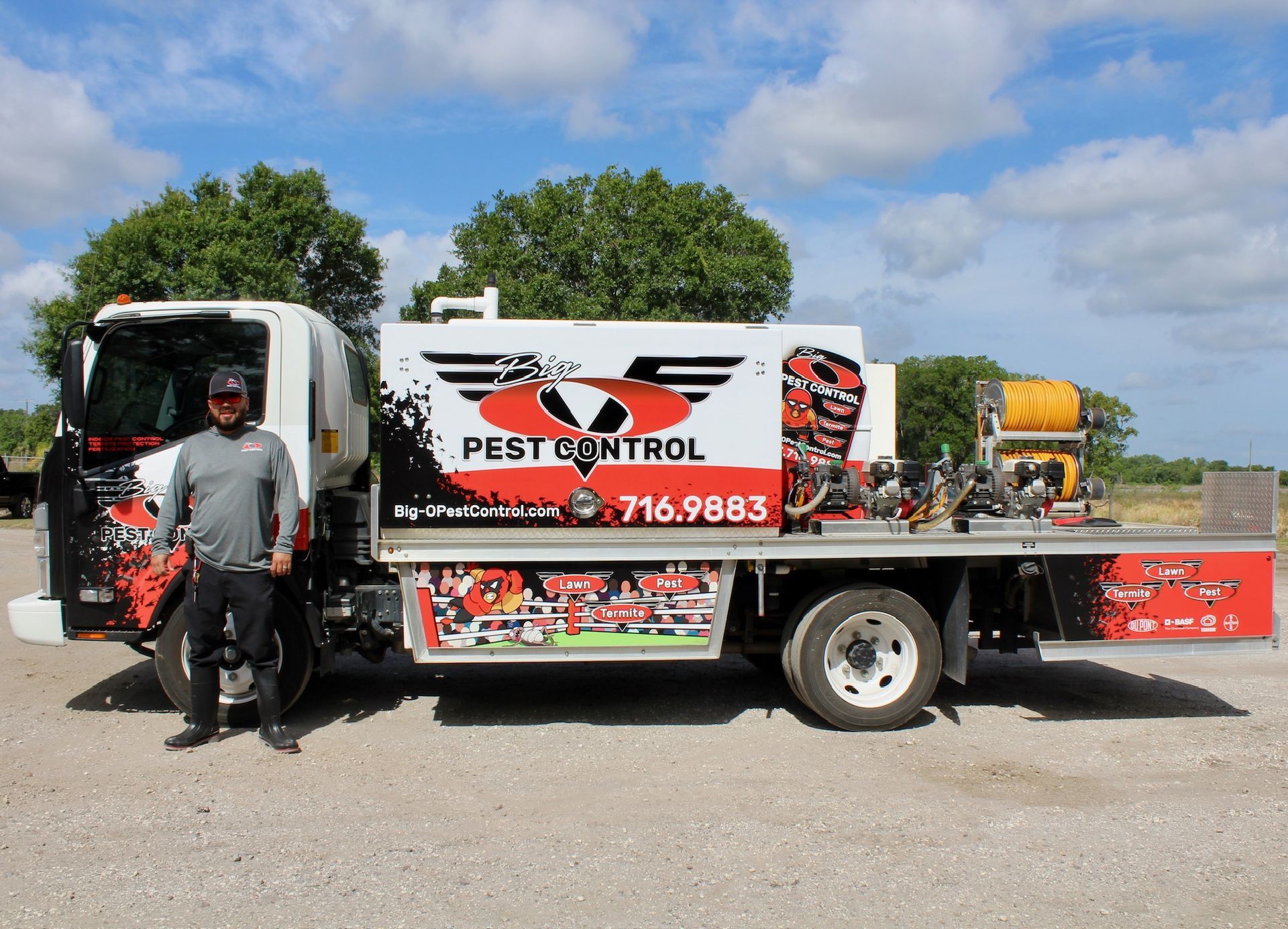A man is standing next to a pest control truck
