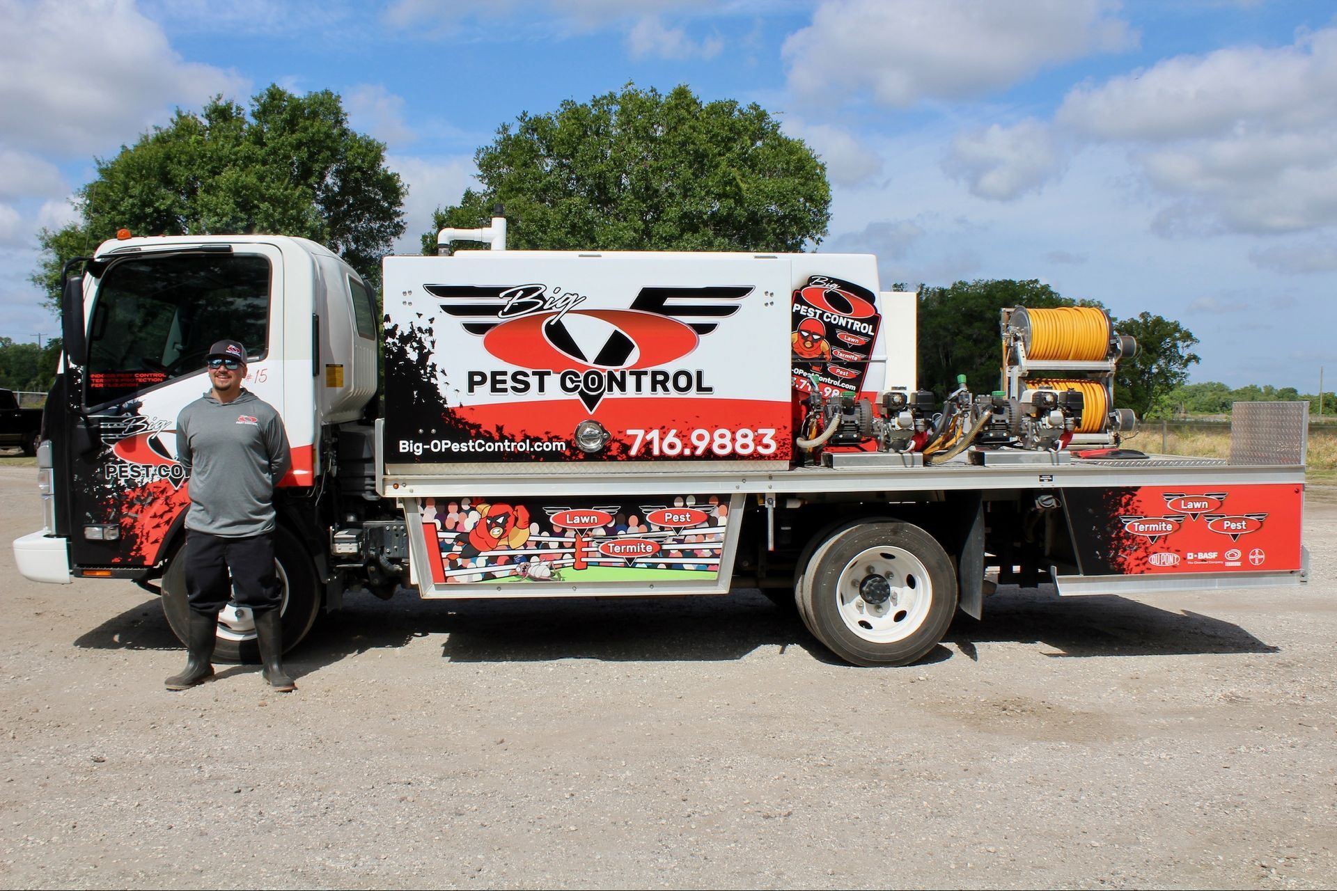 A man is standing next to a pest control truck