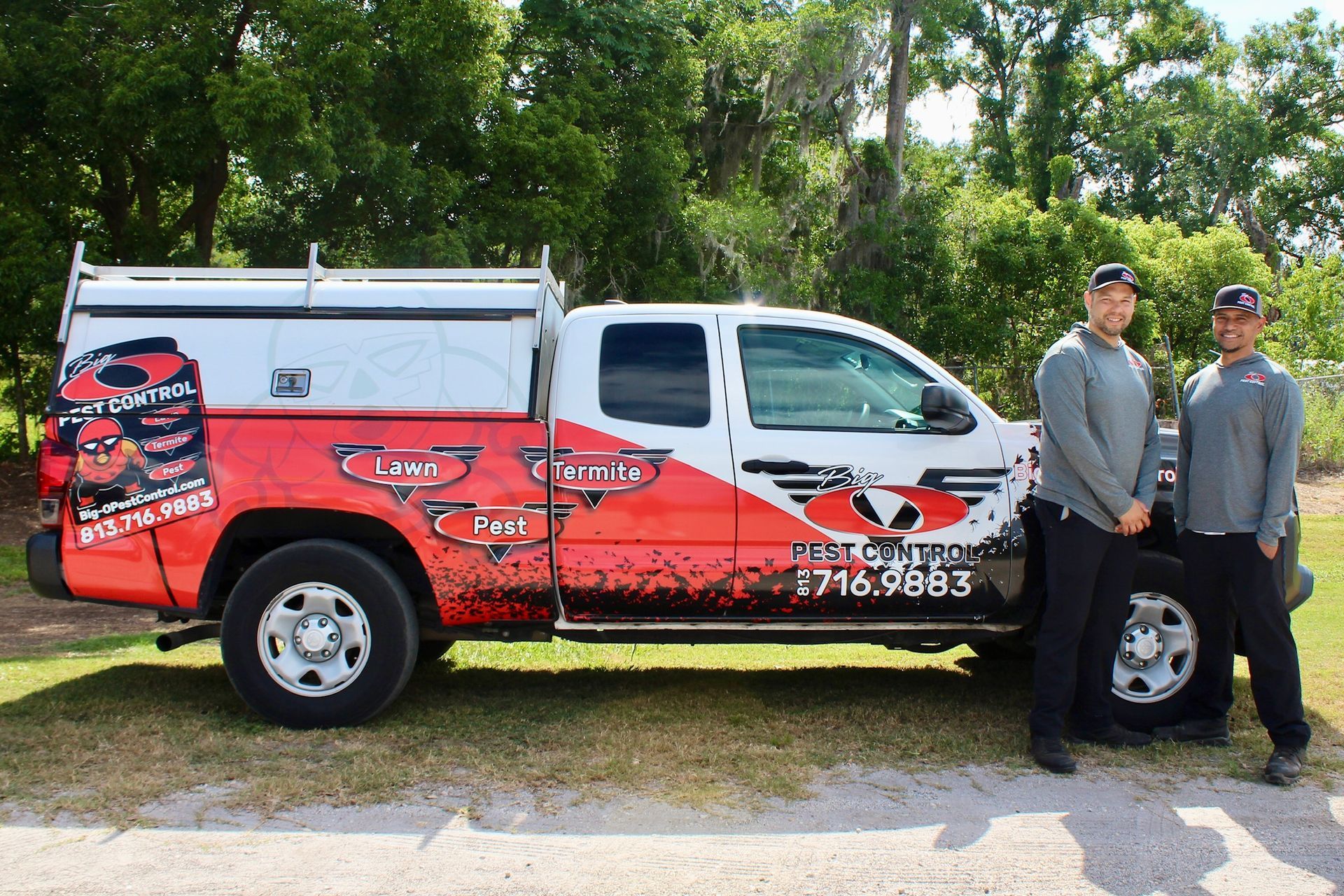 Two men are standing next to a red and white truck.