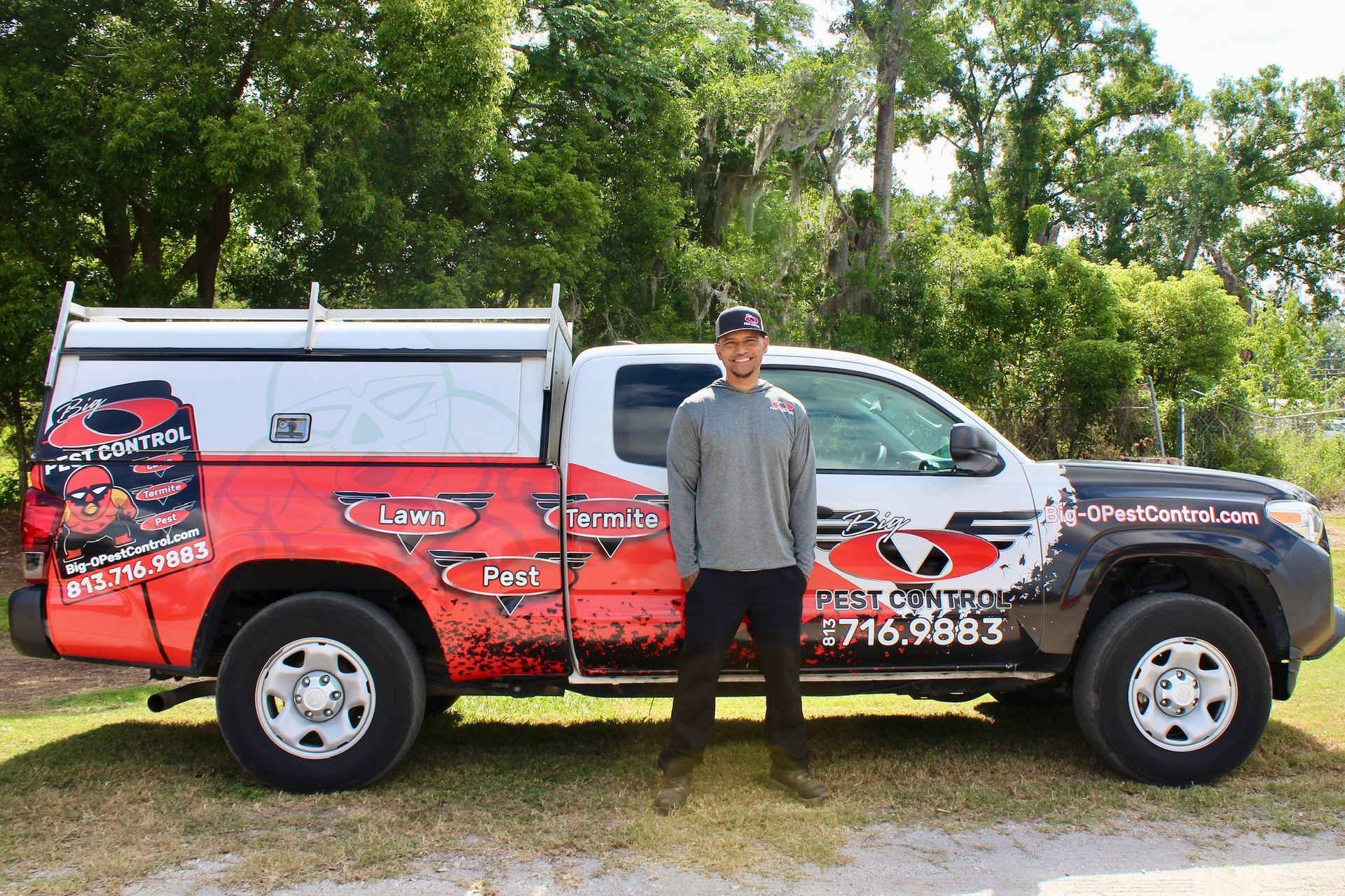 Man standing by a branded work truck with red, black, and white graphics.
