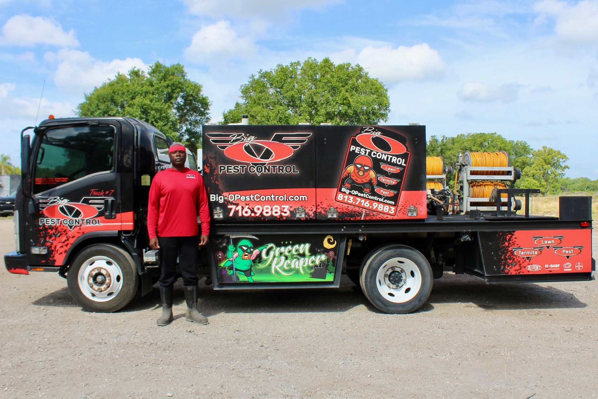 A man in a red shirt is standing next to a red and black truck.