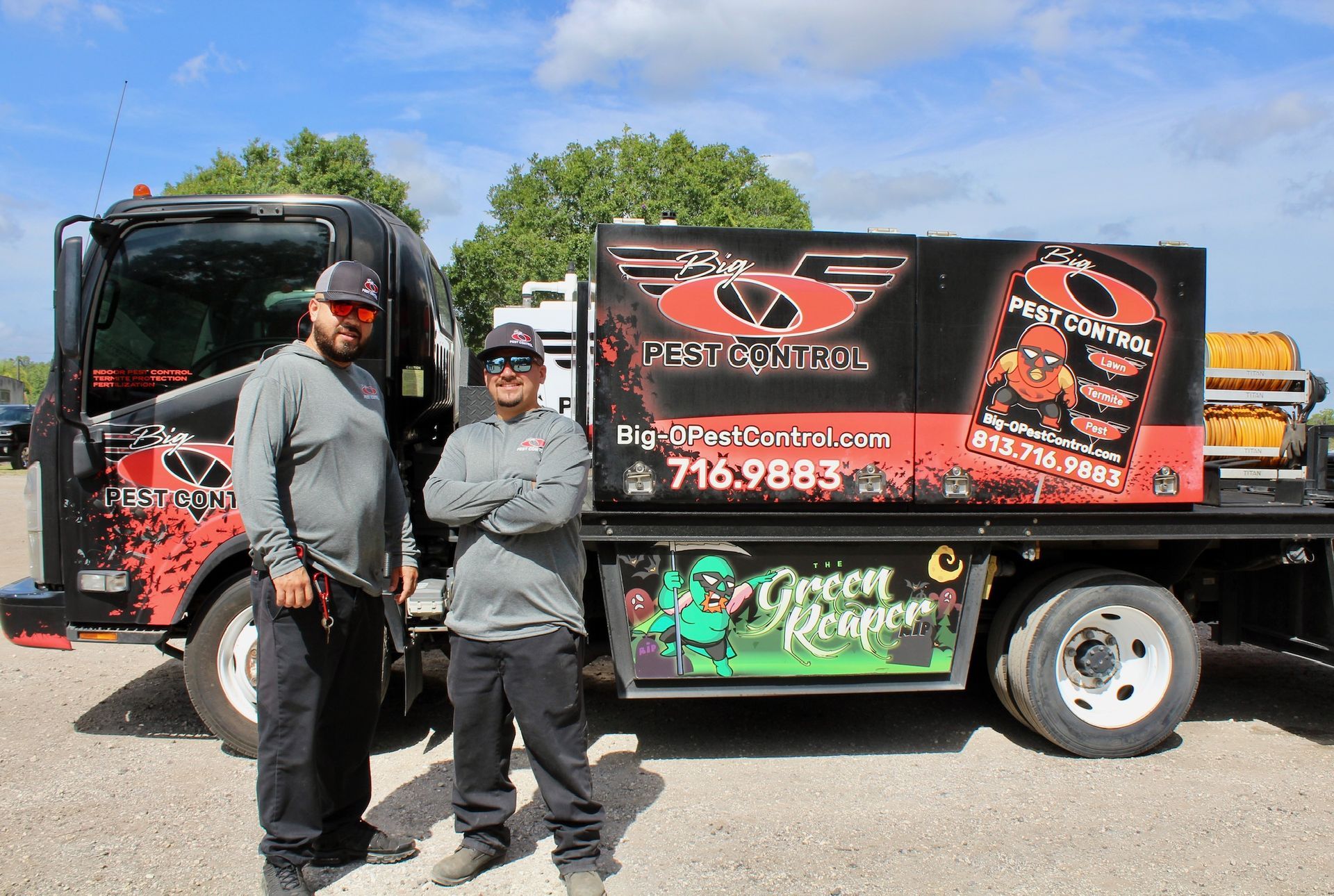 Two men are standing in front of a truck that says pest control.