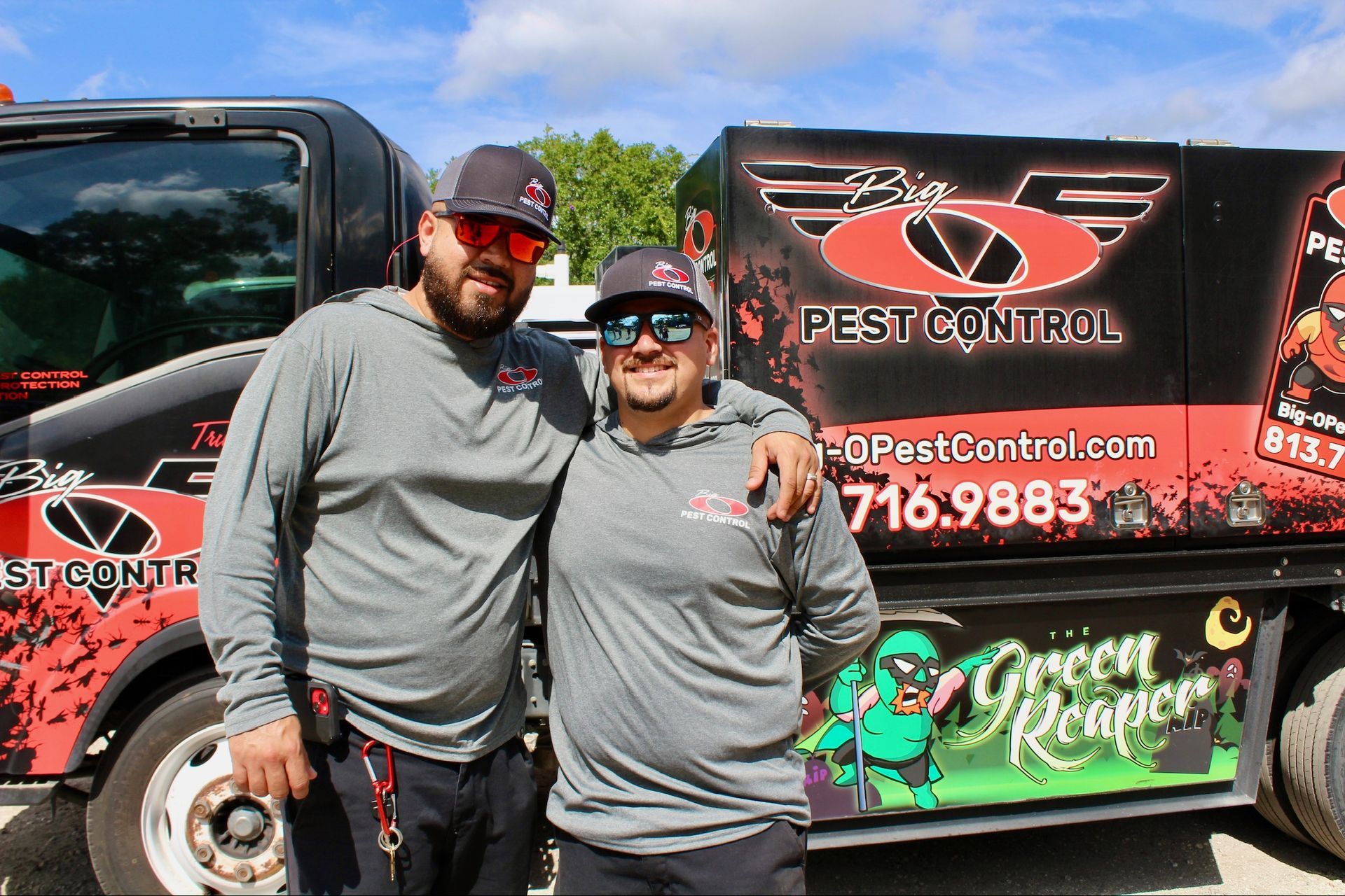 Two men are posing for a picture in front of a pest control truck.