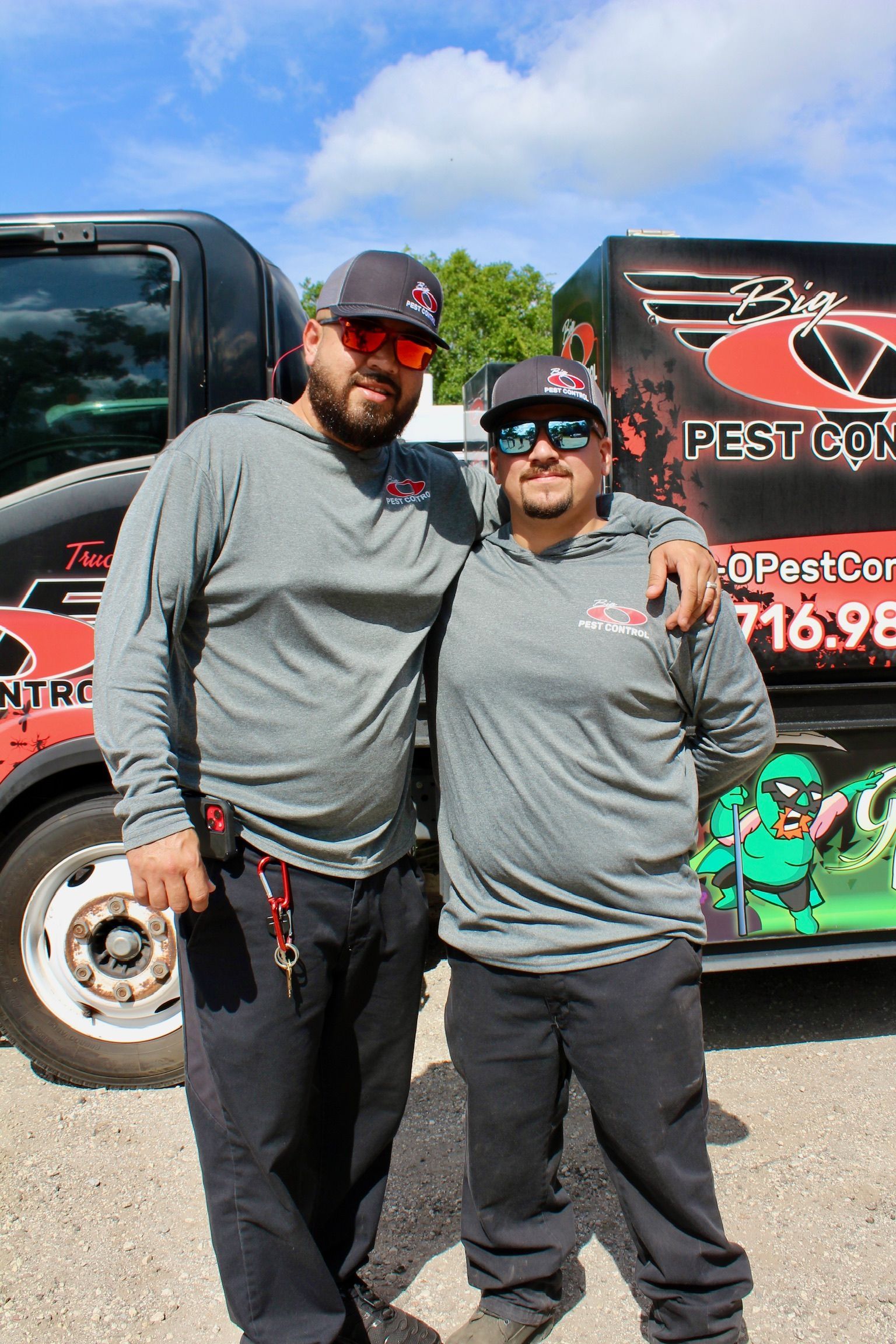 Two men are posing for a picture in front of a truck.