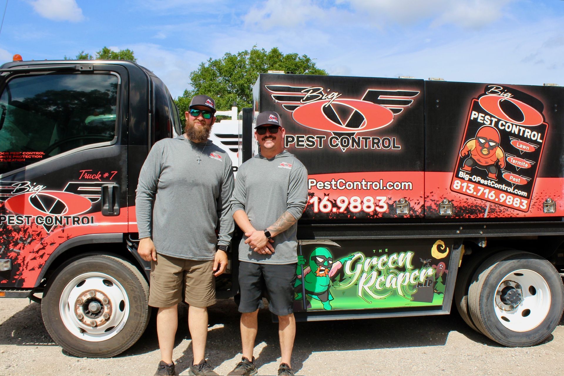 Two men are standing in front of a pest control truck.