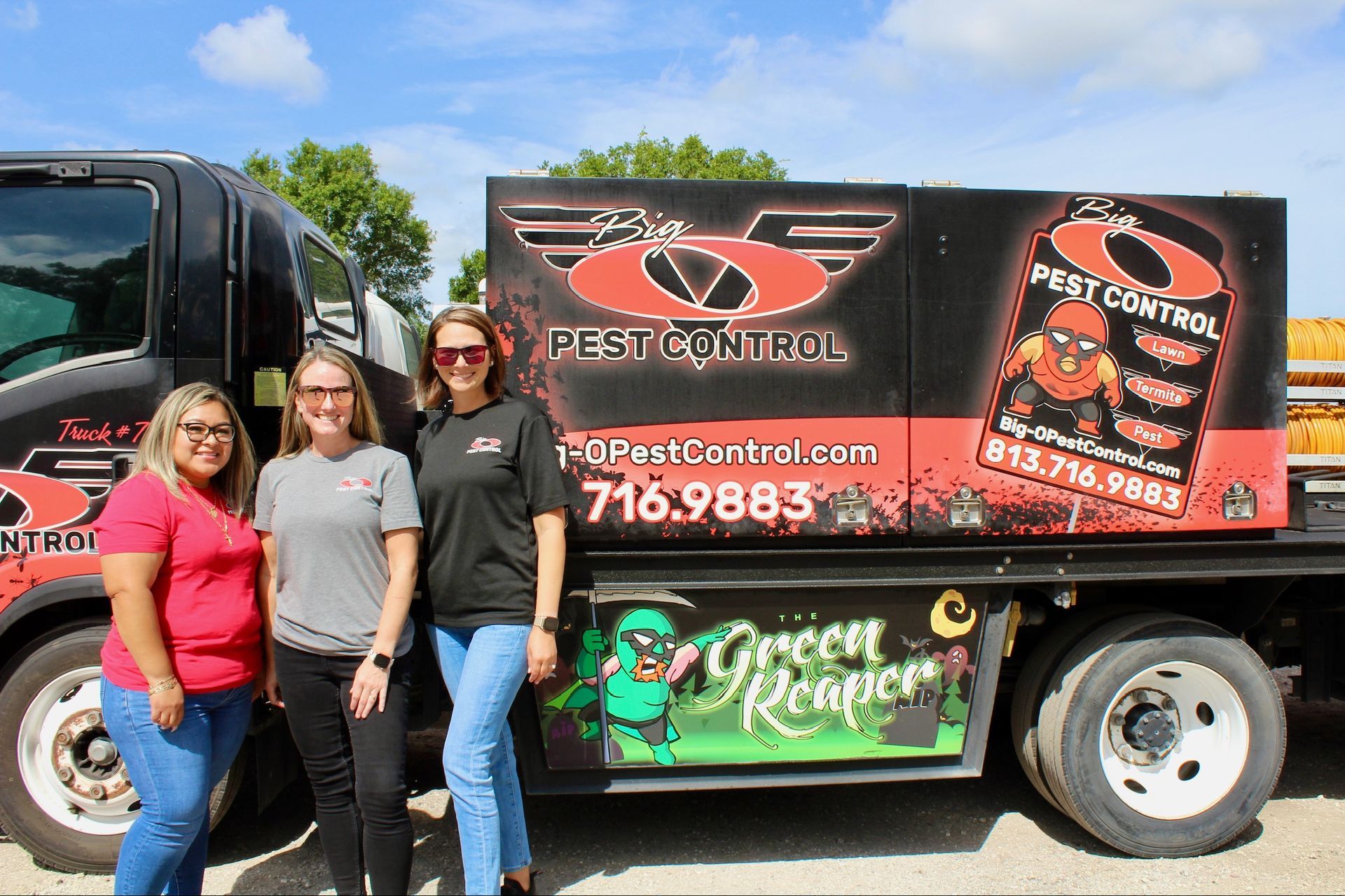 Three women are standing in front of a pest control truck.
