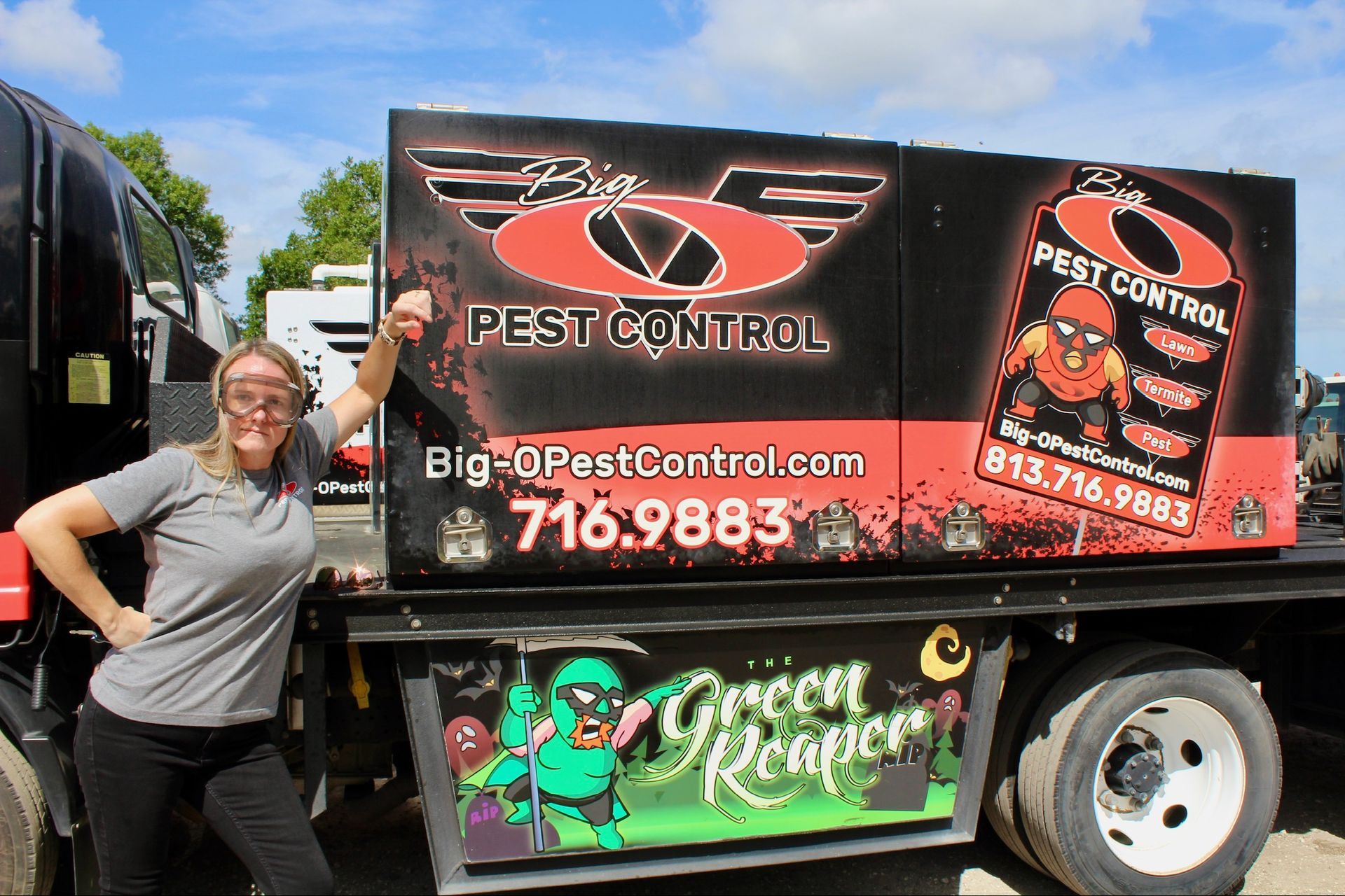 A woman is standing next to a big d pest control truck