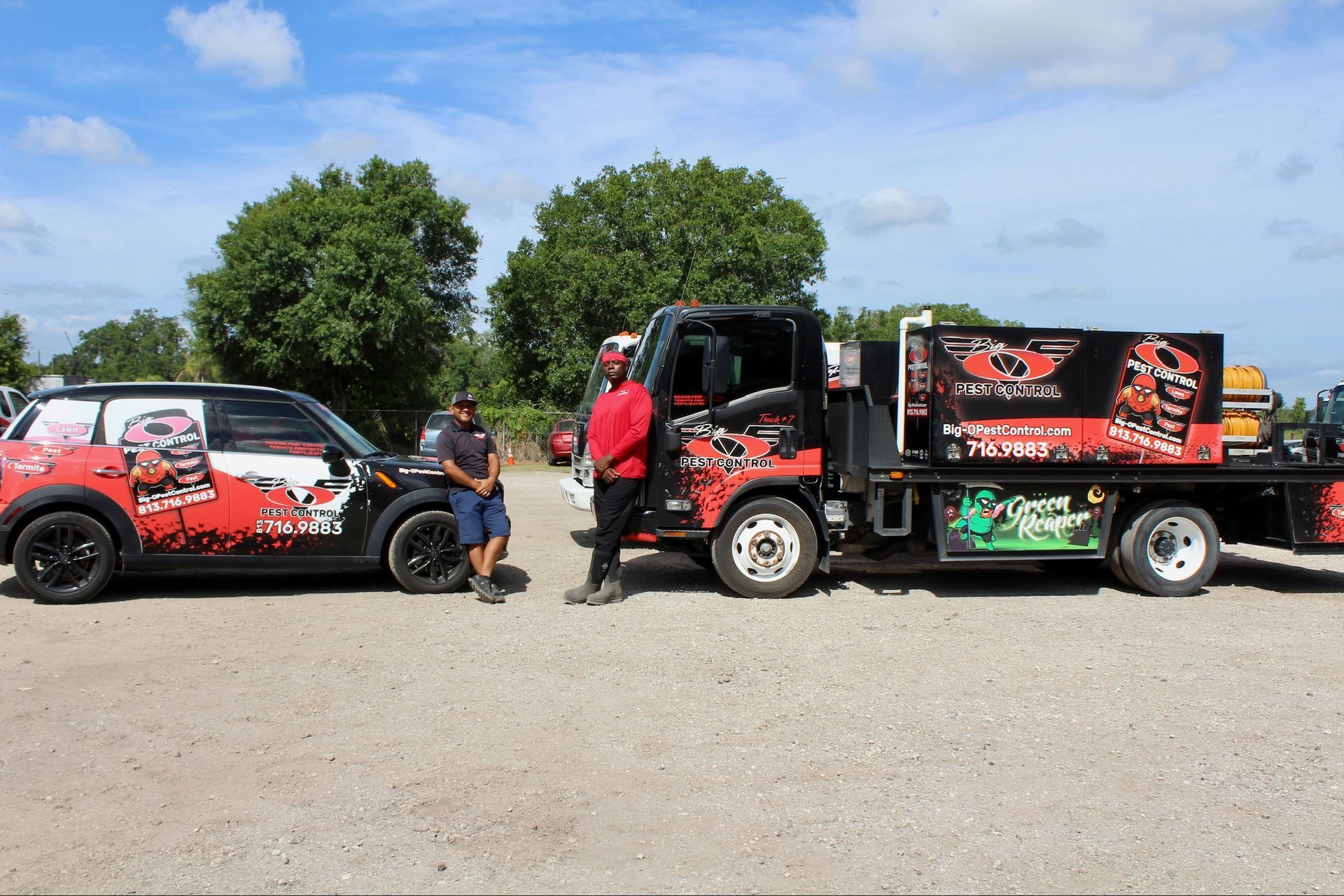 Two men are standing next to a tow truck and a car.