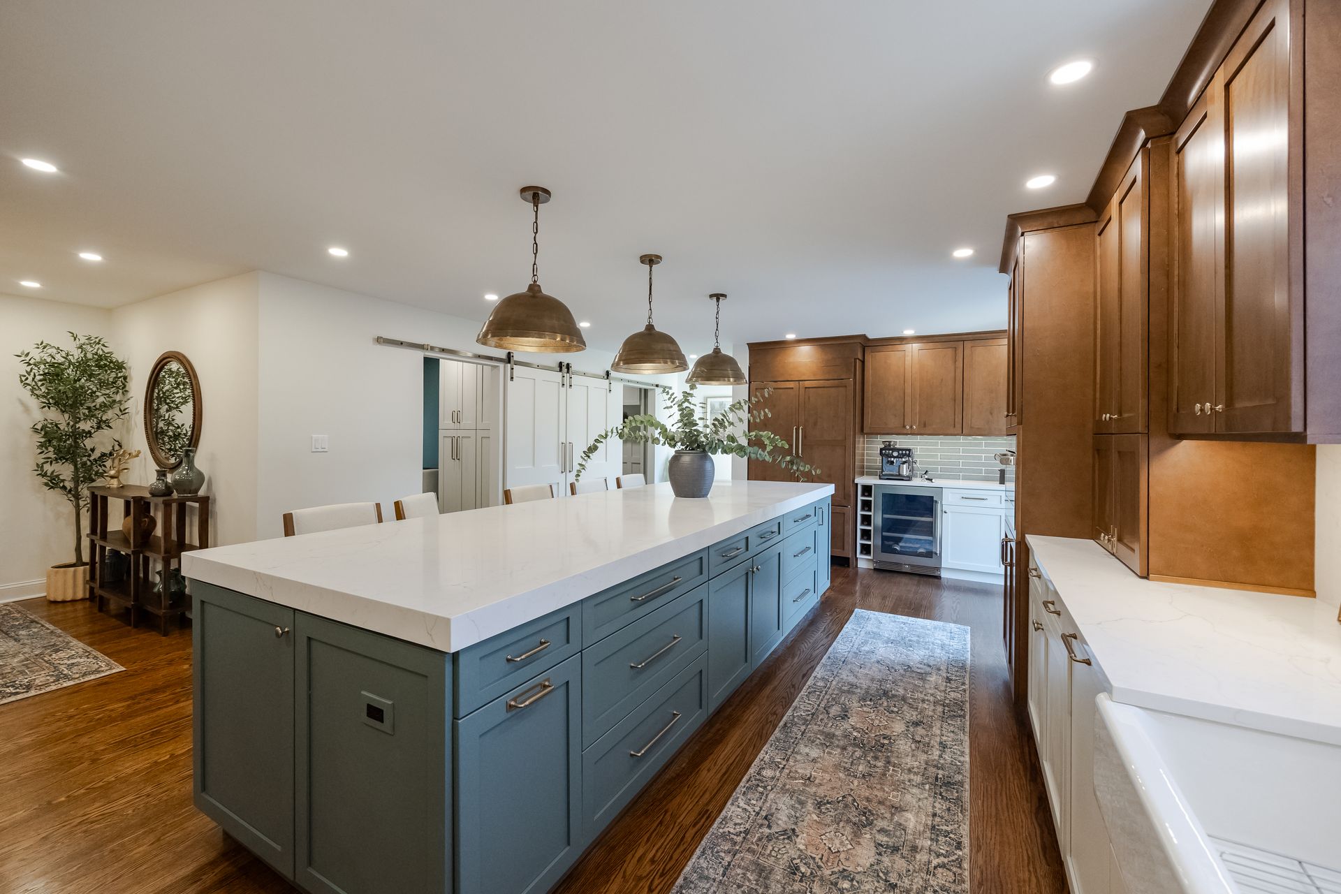 Three people in hard hats and masks review blueprints in a room under renovation; one points upward.