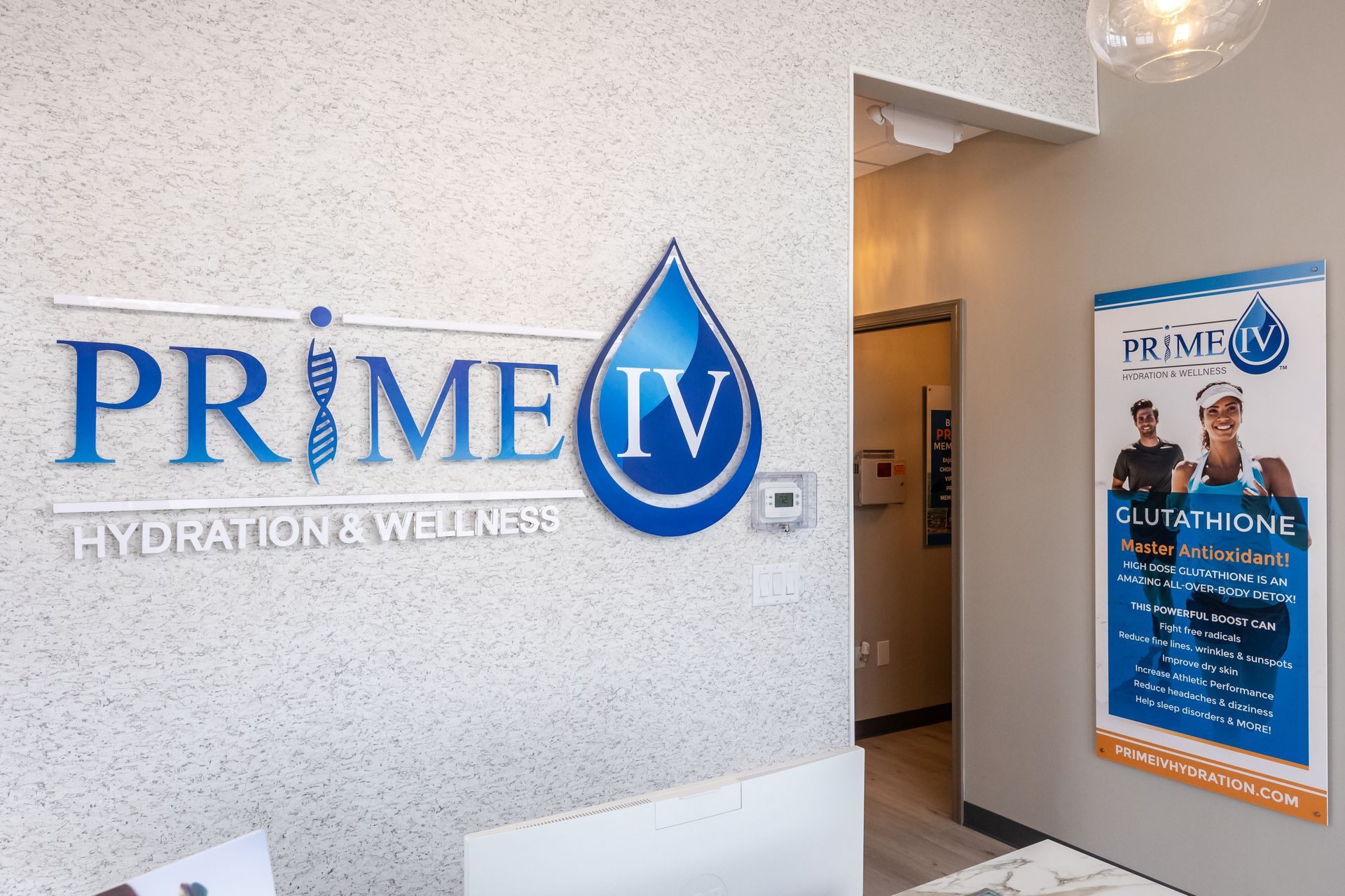 The lobby of Prime IV Hydration & Wellness, featuring a wall logo and a promotional poster for glutathione treatments.