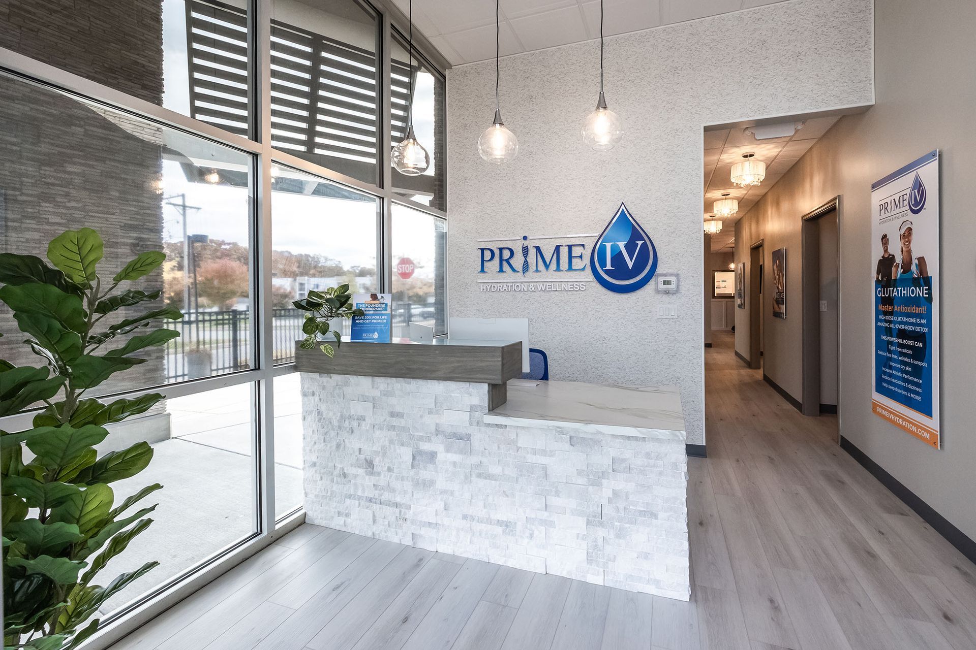 Bright modern office lobby with a white reception desk, glass windows, and hallway signage.