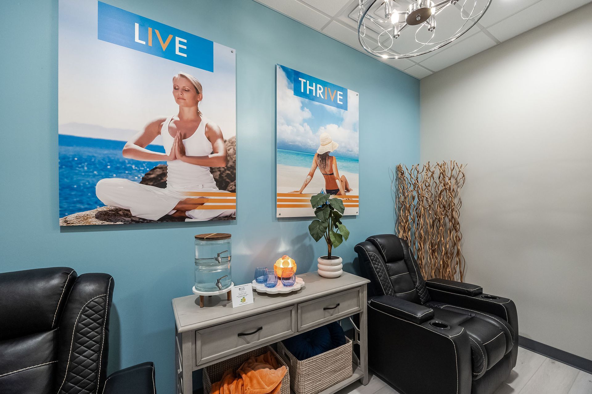 Clinic waiting area with black chairs, teal wall art, and a small table with decor.