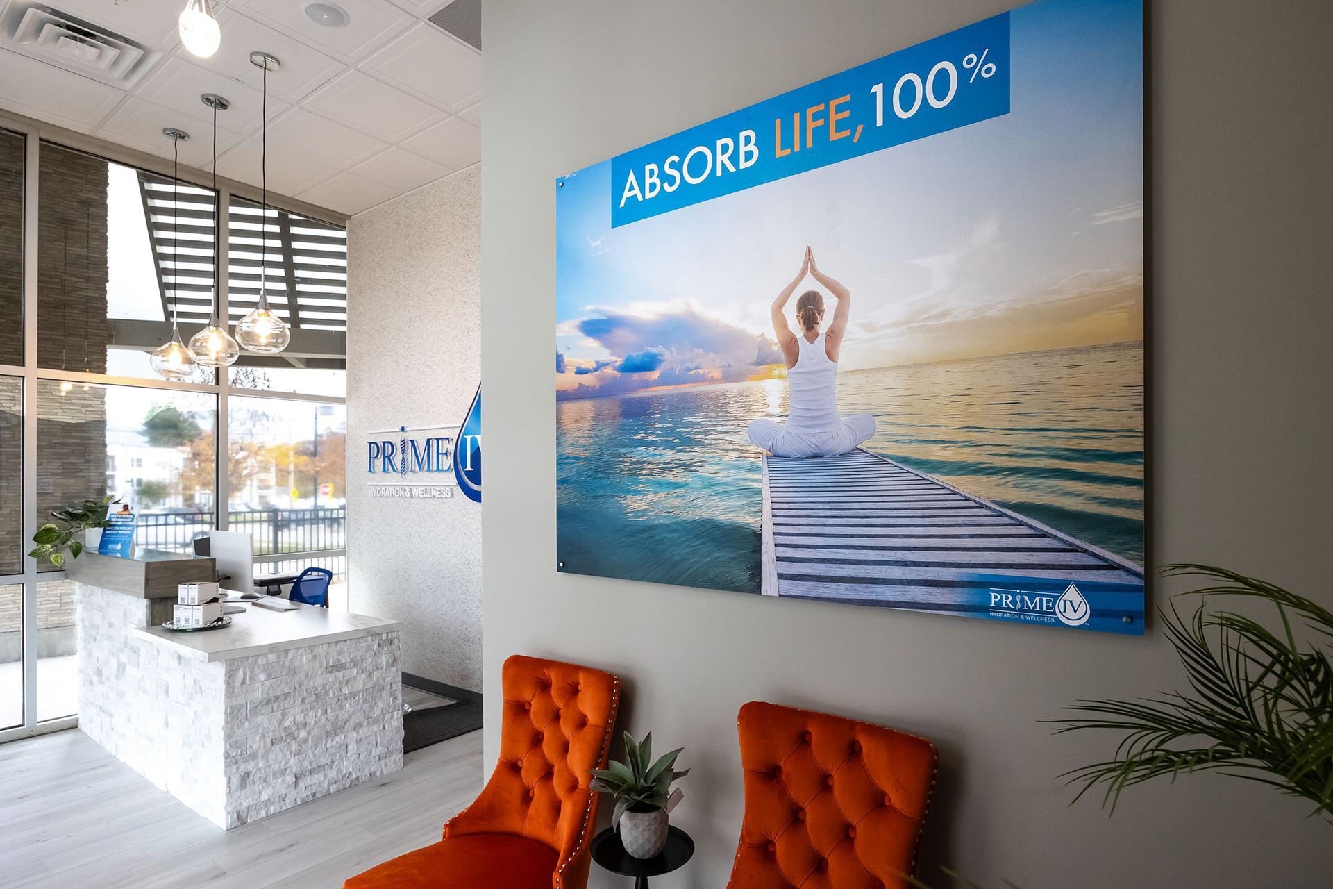 Bright office lobby with orange chairs and a large wall poster.