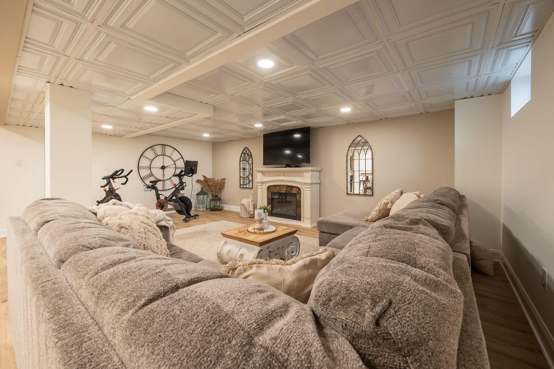 Three people in hard hats and masks review blueprints in a room under renovation; one points upward.
