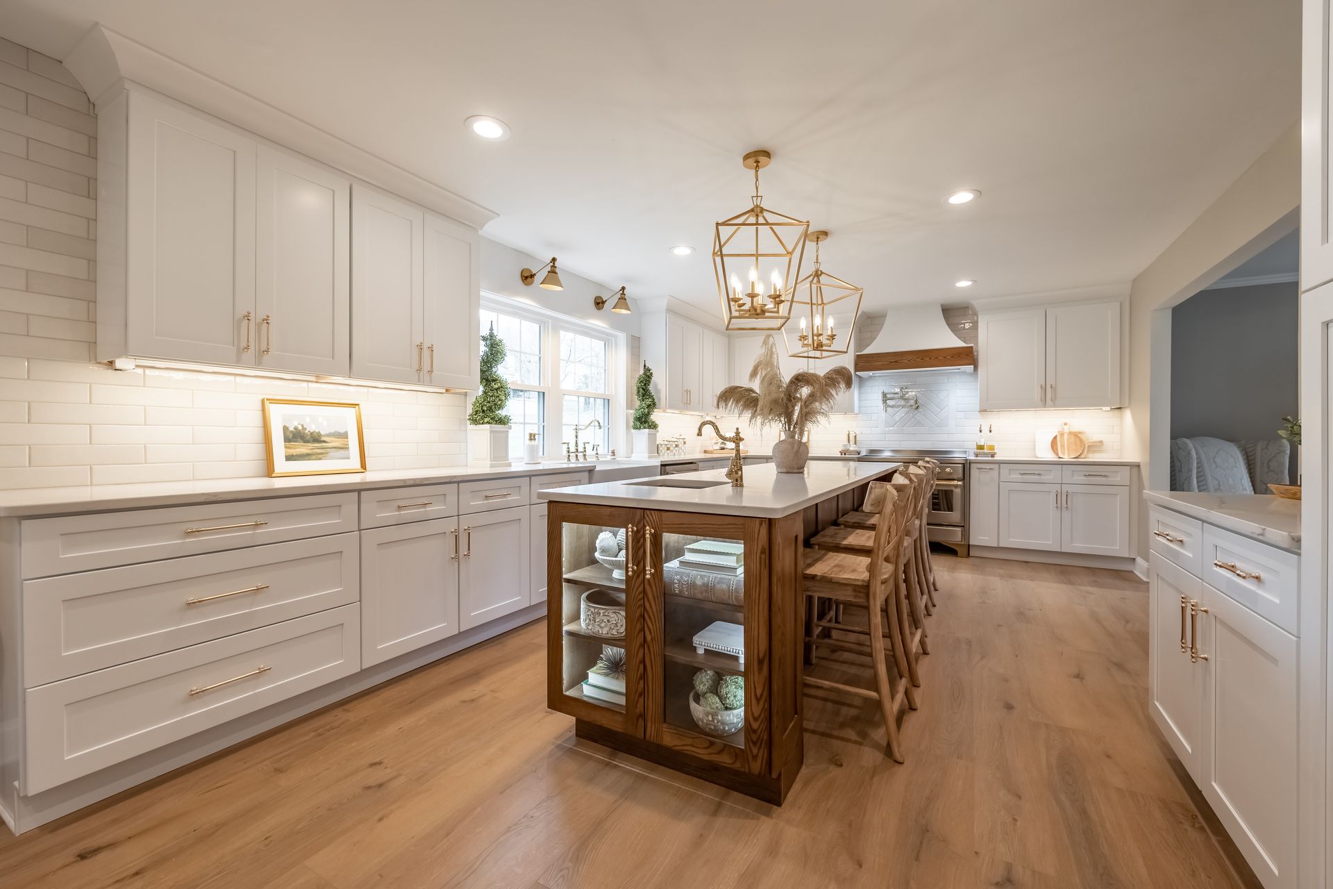 Spacious, modern kitchen with white cabinets, wood island, gold accents, and hardwood floors.