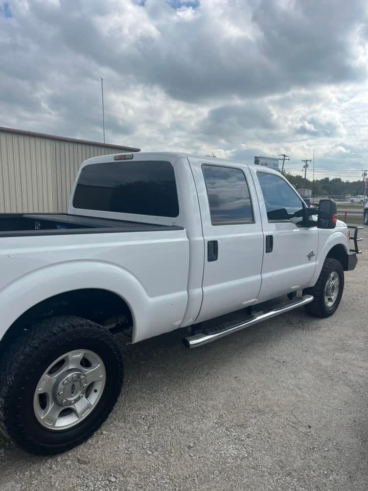 A white truck is parked in a gravel lot in front of a building.