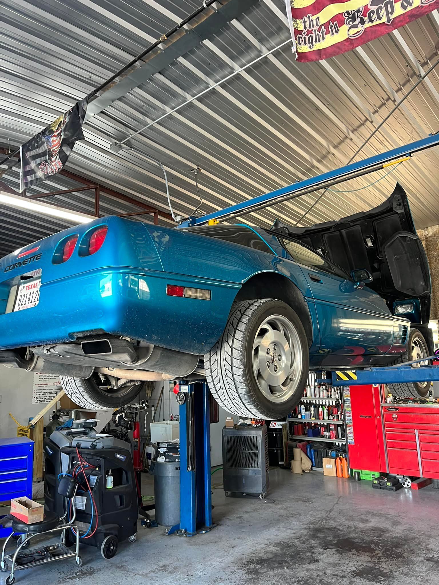 A blue car is sitting on a lift in a garage.
