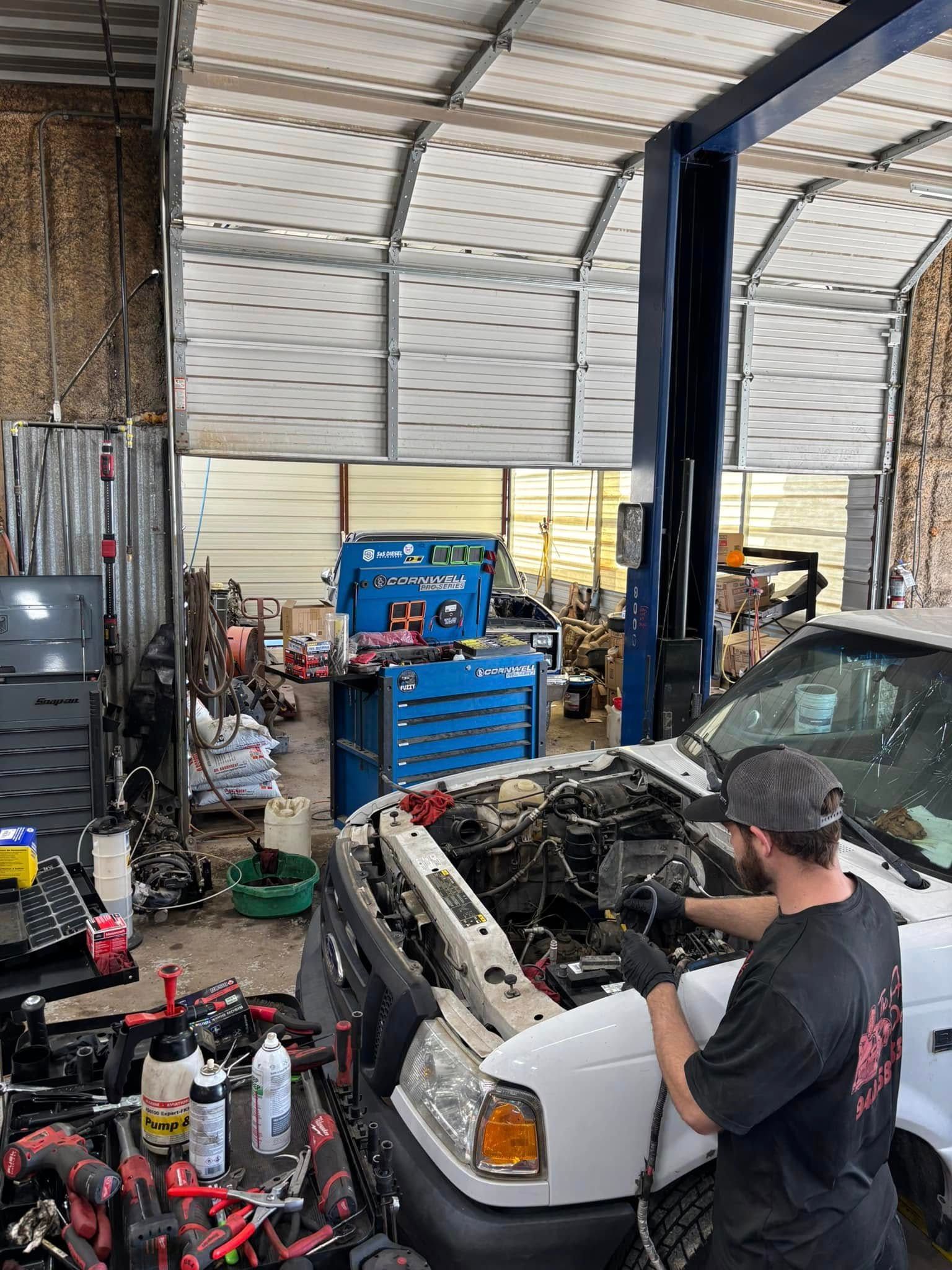 A man is working on the engine of a truck in a garage.