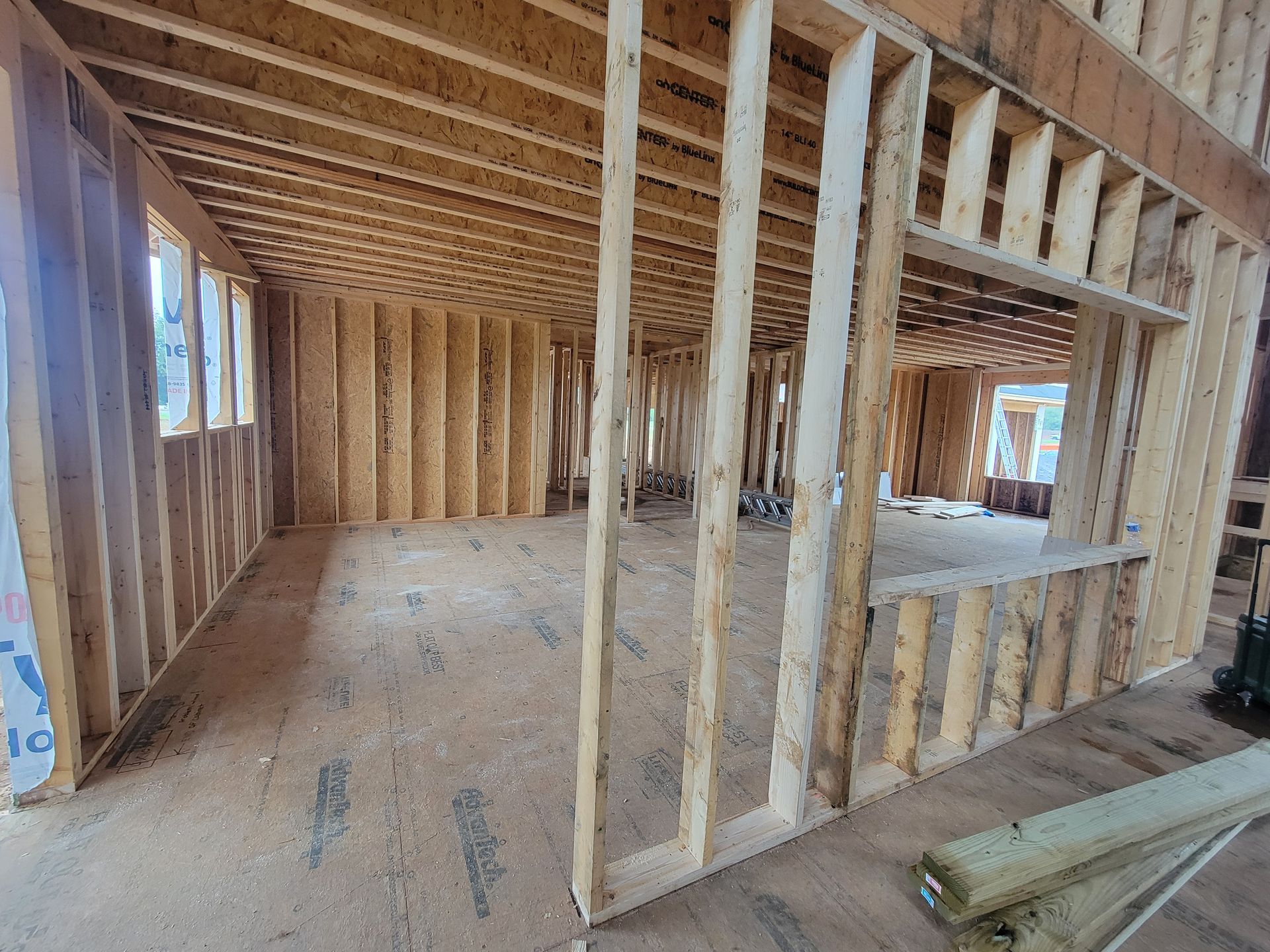 Framing stage of a new construction home showing open walls for the future kitchen, pantry, and living areas before cabinetry installation.