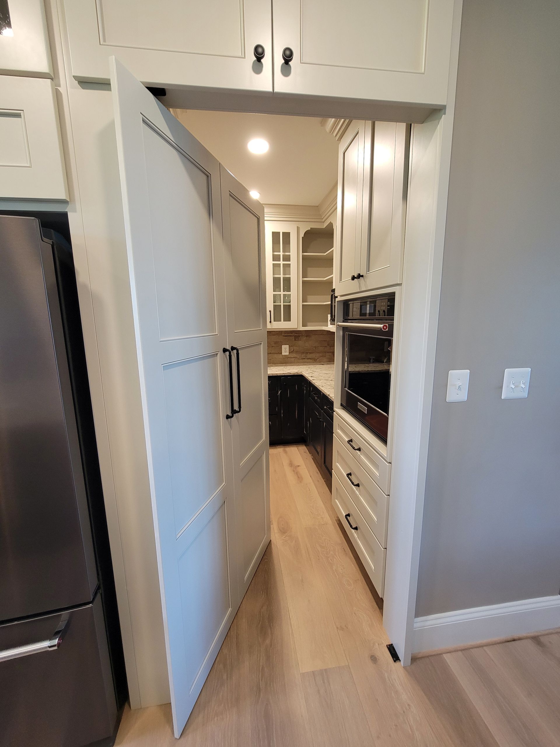Completed hidden pantry door fully blended into the kitchen cabinetry using bookshelf style pivot hardware.