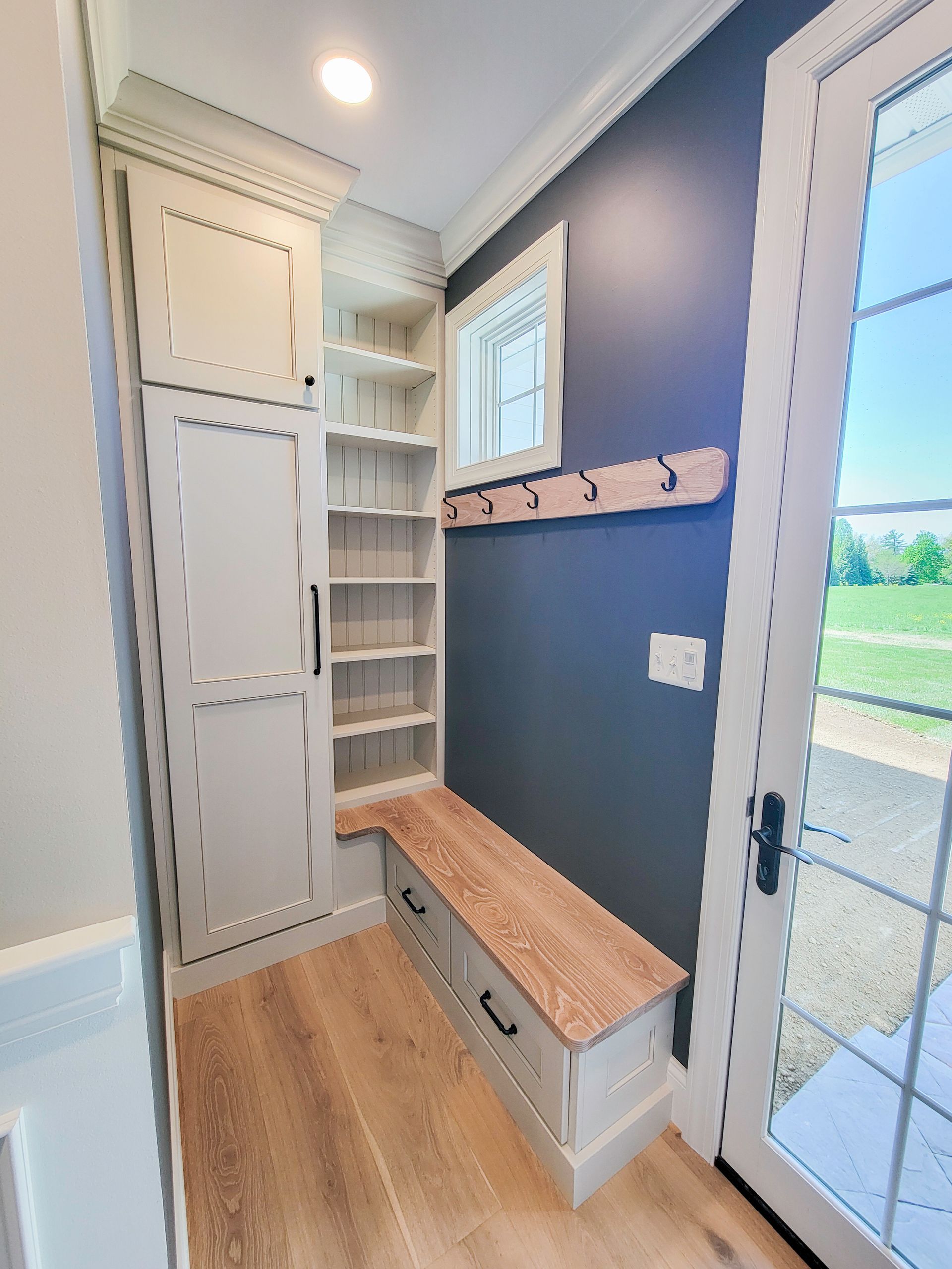 Finished back door closet nook featuring hooks, trim details, and built in charm added to a small transitional space.