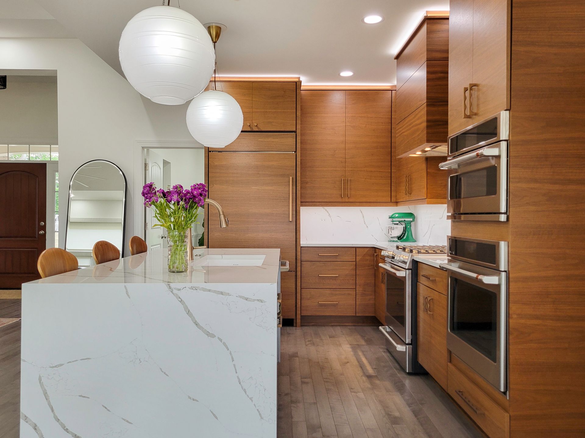 Modern kitchen with white island, wood cabinets, pendant lights, and stainless steel appliances