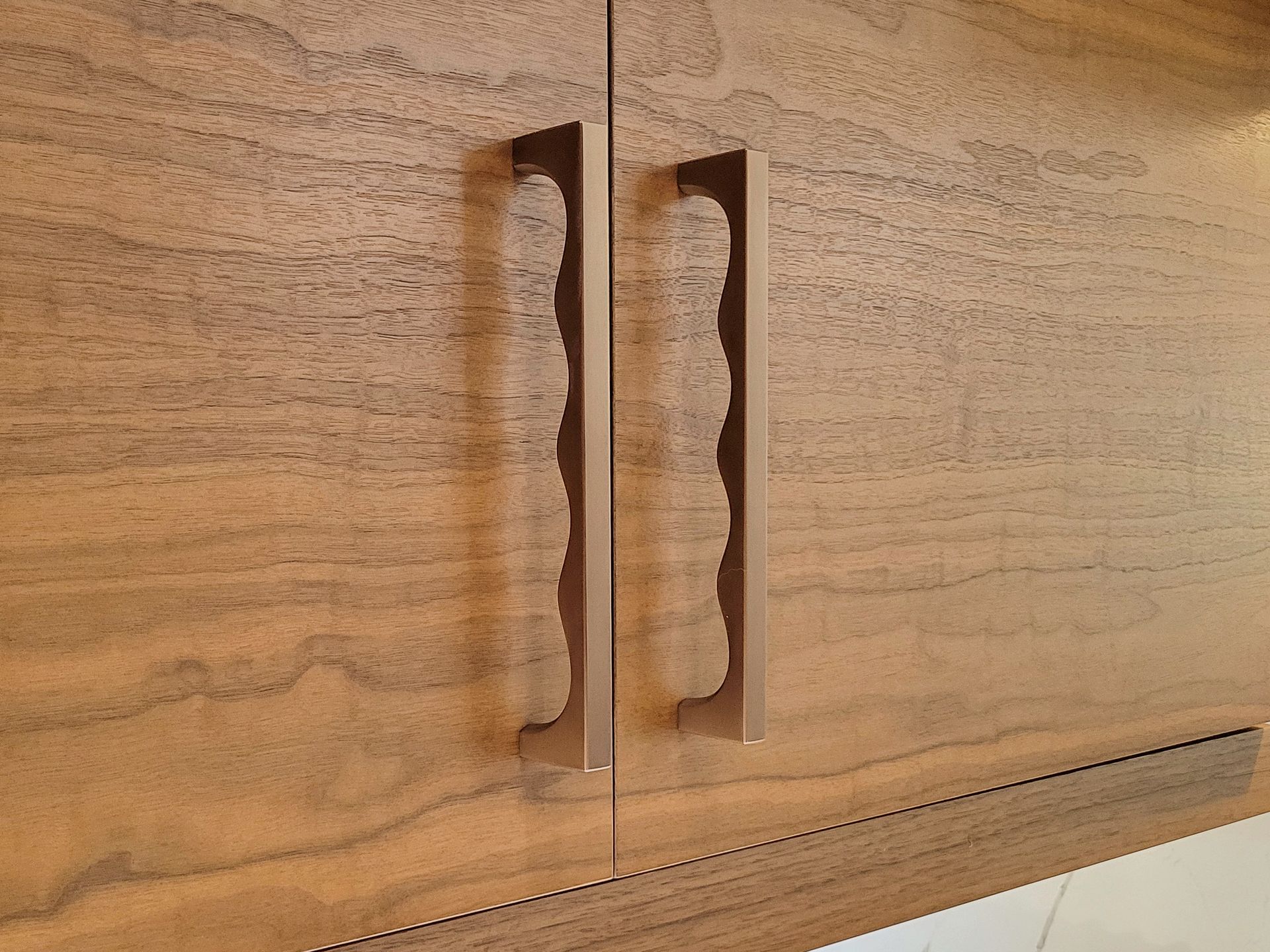 Wooden cabinet doors with vertical handles and a lower drawer edge.