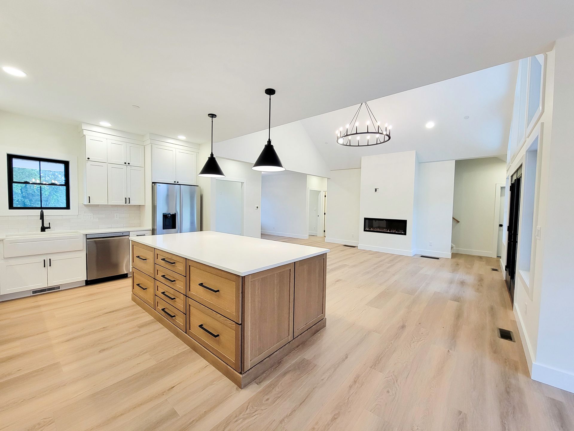 Bright modern kitchen with a large wooden island, pendant lights, white cabinets, and light wood floors.