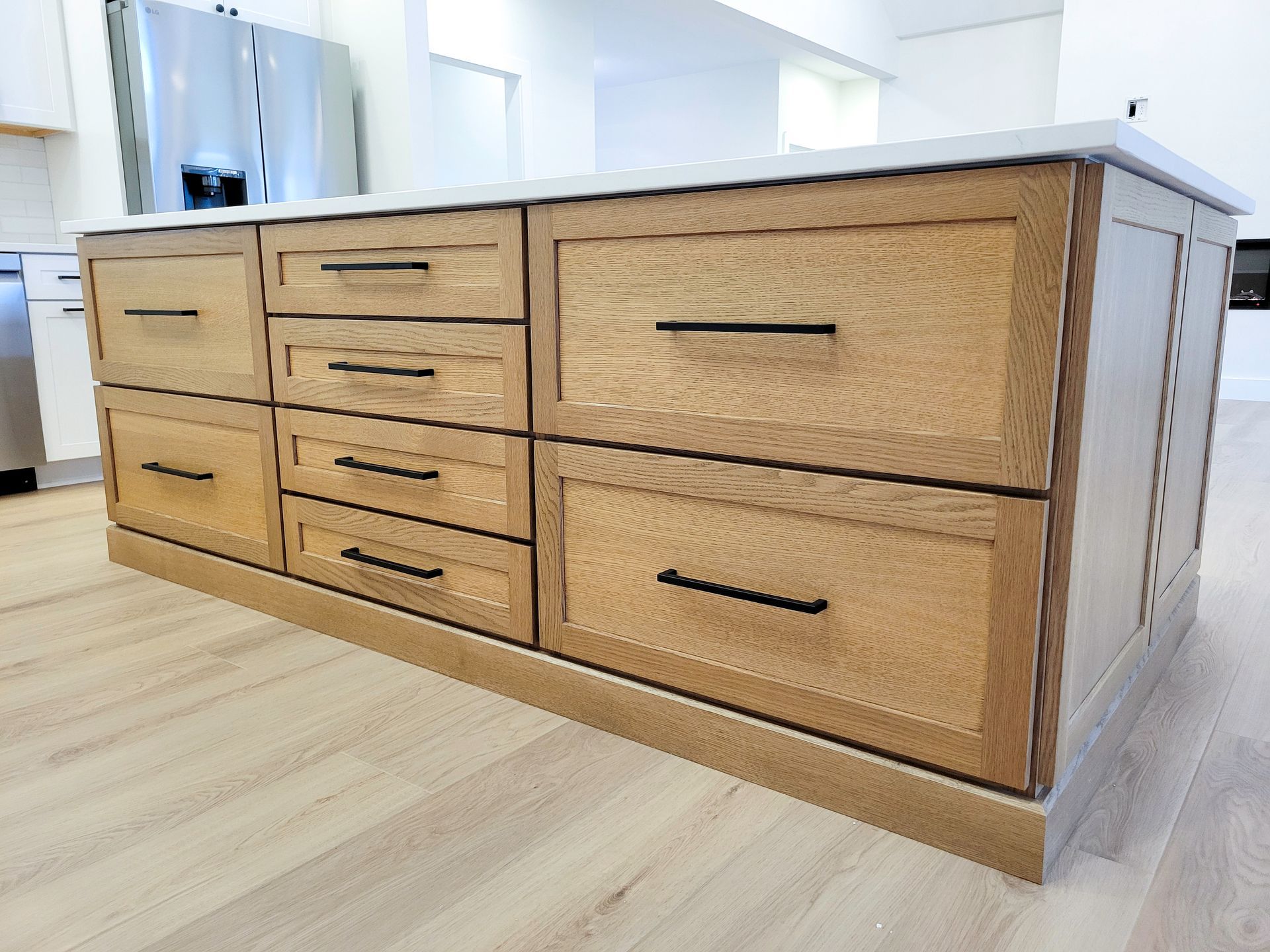 Light wood kitchen island with woven cabinet fronts and drawers in a bright modern kitchen