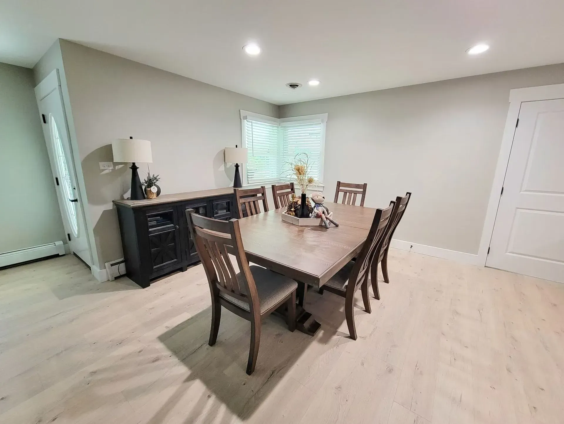 Dining room with wood table and chairs, black buffet, and light flooring.