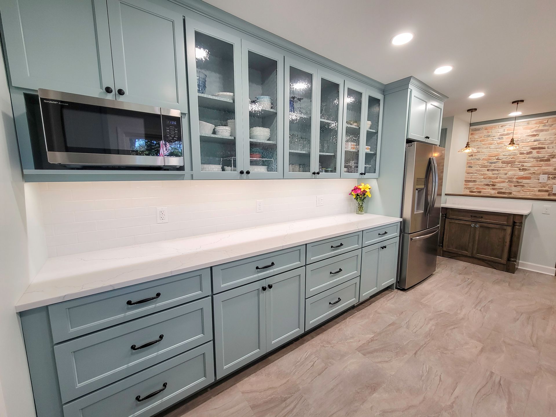 Blue kitchen cabinets with stainless steel appliances and a white countertop.