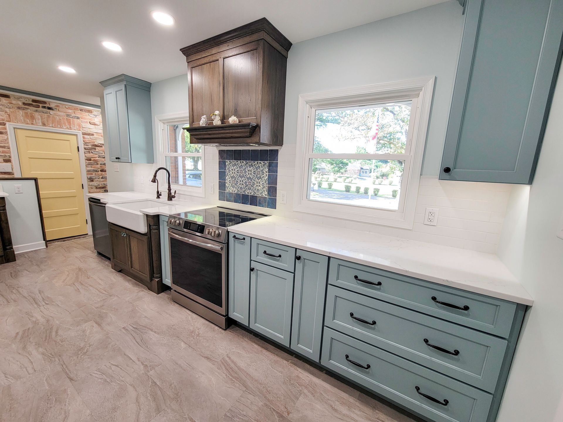 Kitchen with blue and brown cabinets, white countertops, a stove, and a farmhouse sink.
