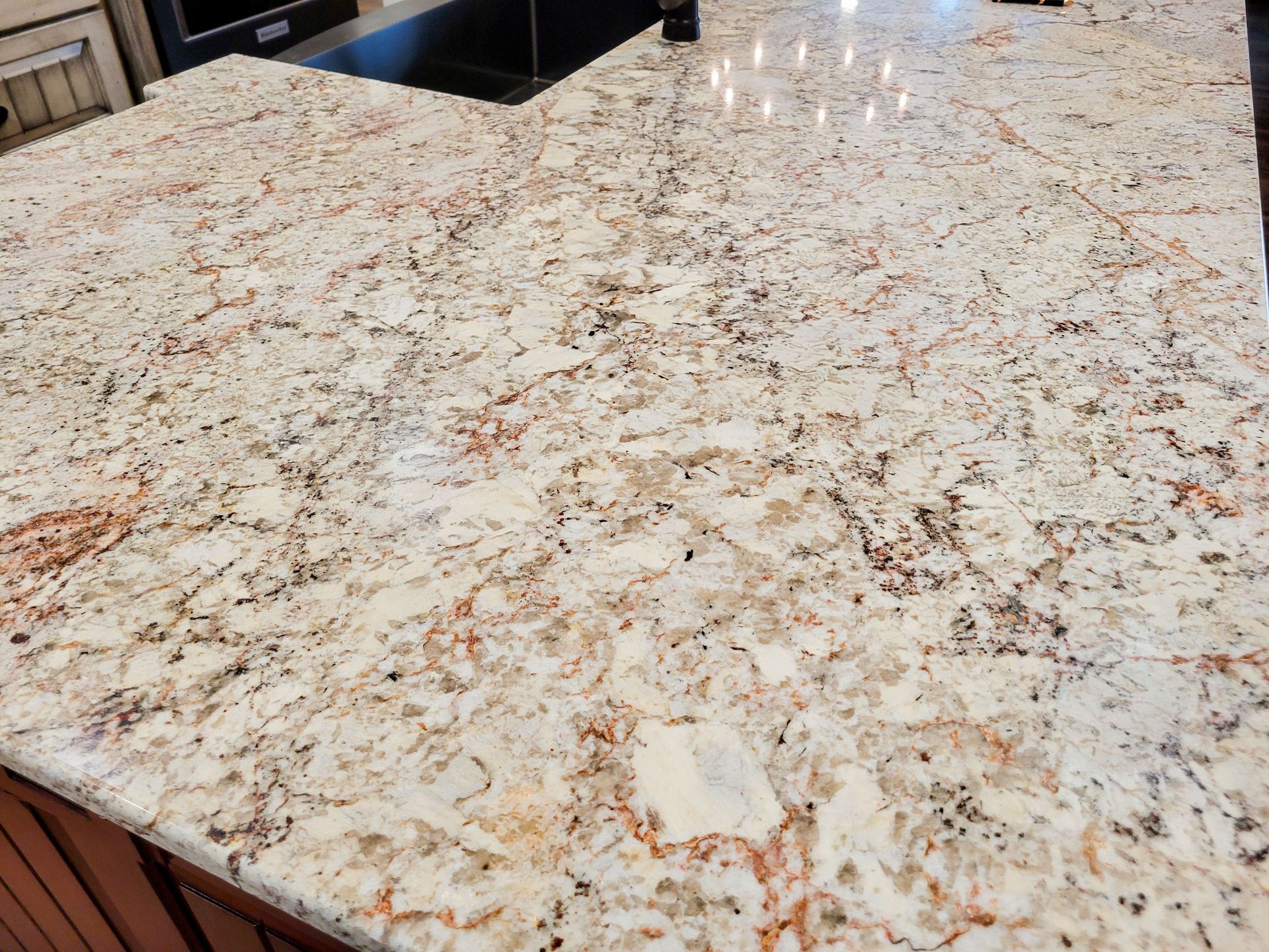 Close-up of a granite countertop with white, tan, and reddish-brown veining and speckling.