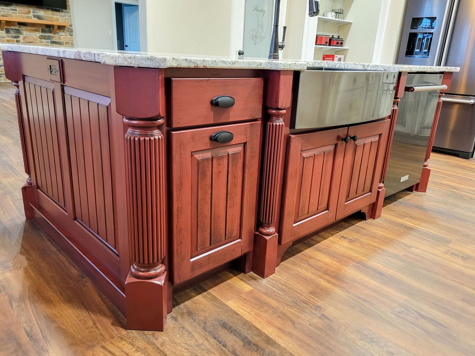 Kitchen island with red cabinets, granite countertop, and stainless steel sink.