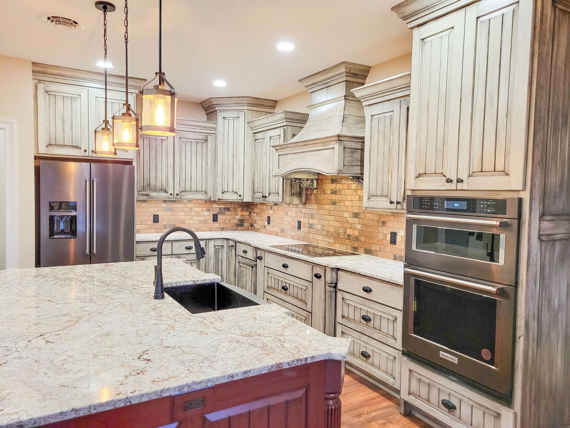 Kitchen with cream-colored distressed cabinets, granite countertops, and stainless steel appliances.