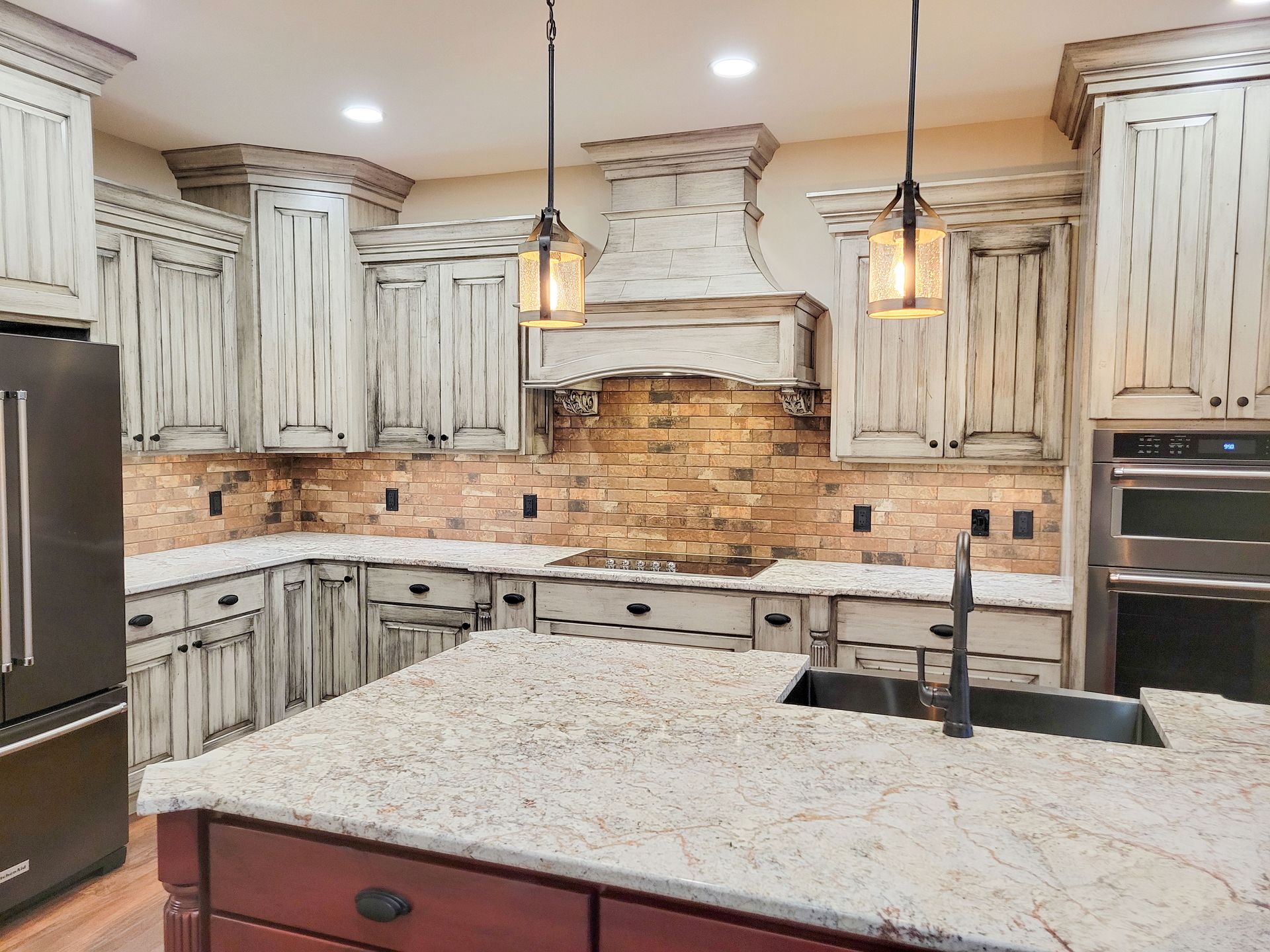 Kitchen with distressed white cabinets, brick backsplash, and granite countertop island.